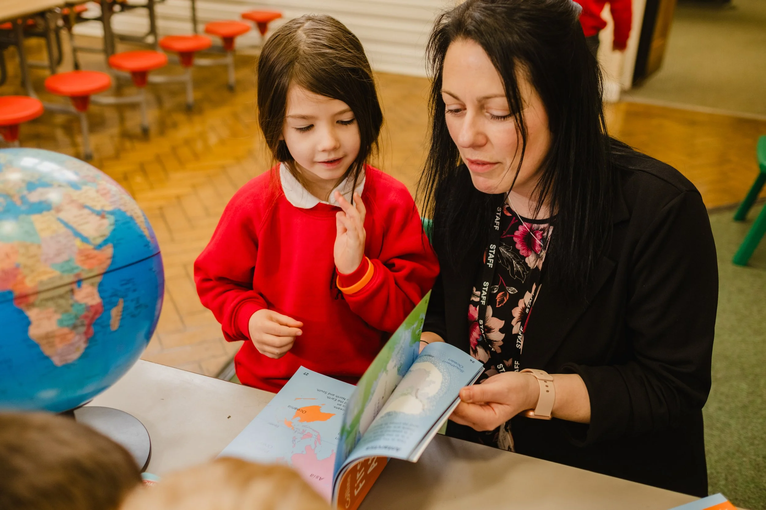 A teacher and student looking at a book at Marsden Infant and Nursery School in Marsden, West Yorkshire.