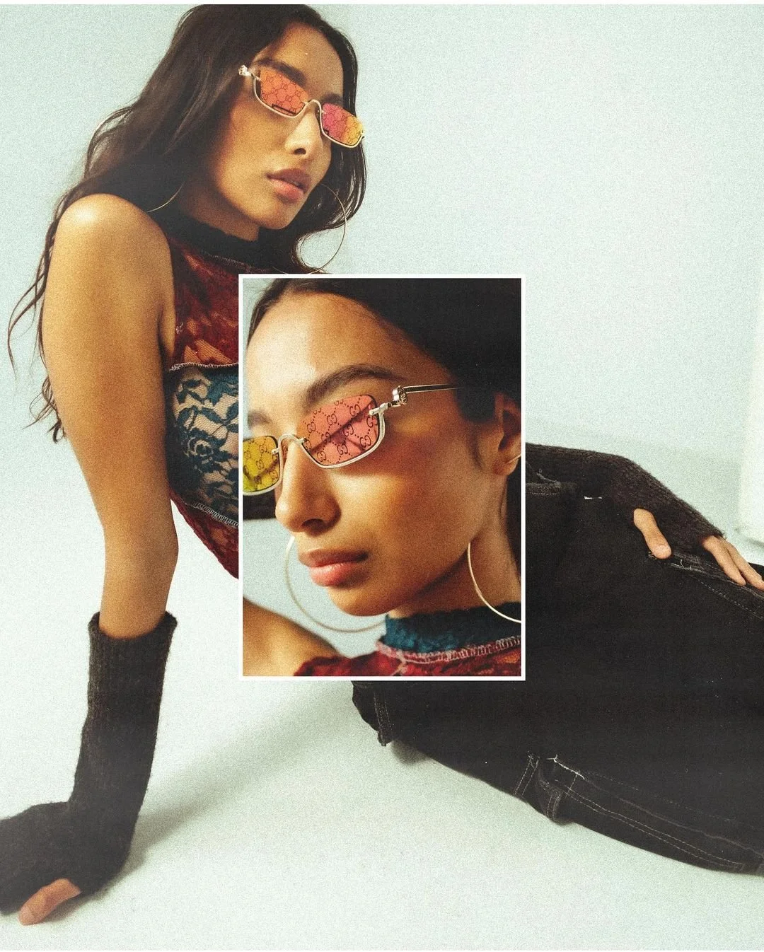 A woman with long dark hair wearing reflective sunglasses with Gucci logo, a black choker, large hoop earrings, a sleeveless top with lace and velvet details, black fingerless gloves, and black ripped jeans, leaning on her hands on a white surface, w