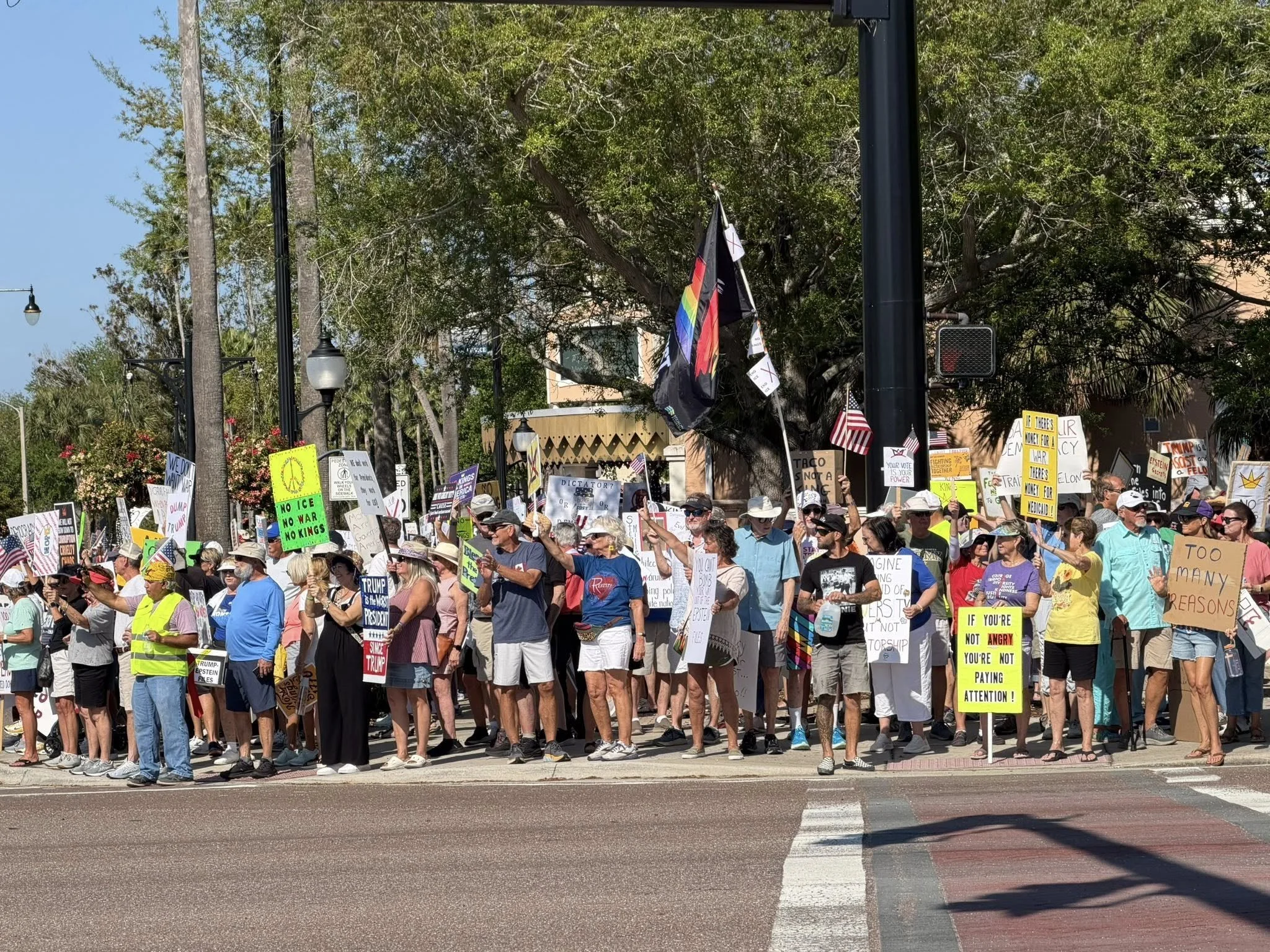 Large crowd of people gathered on a city street during a protest or march, holding various signs and banners, with the U.S. Capitol building visible in the background.
