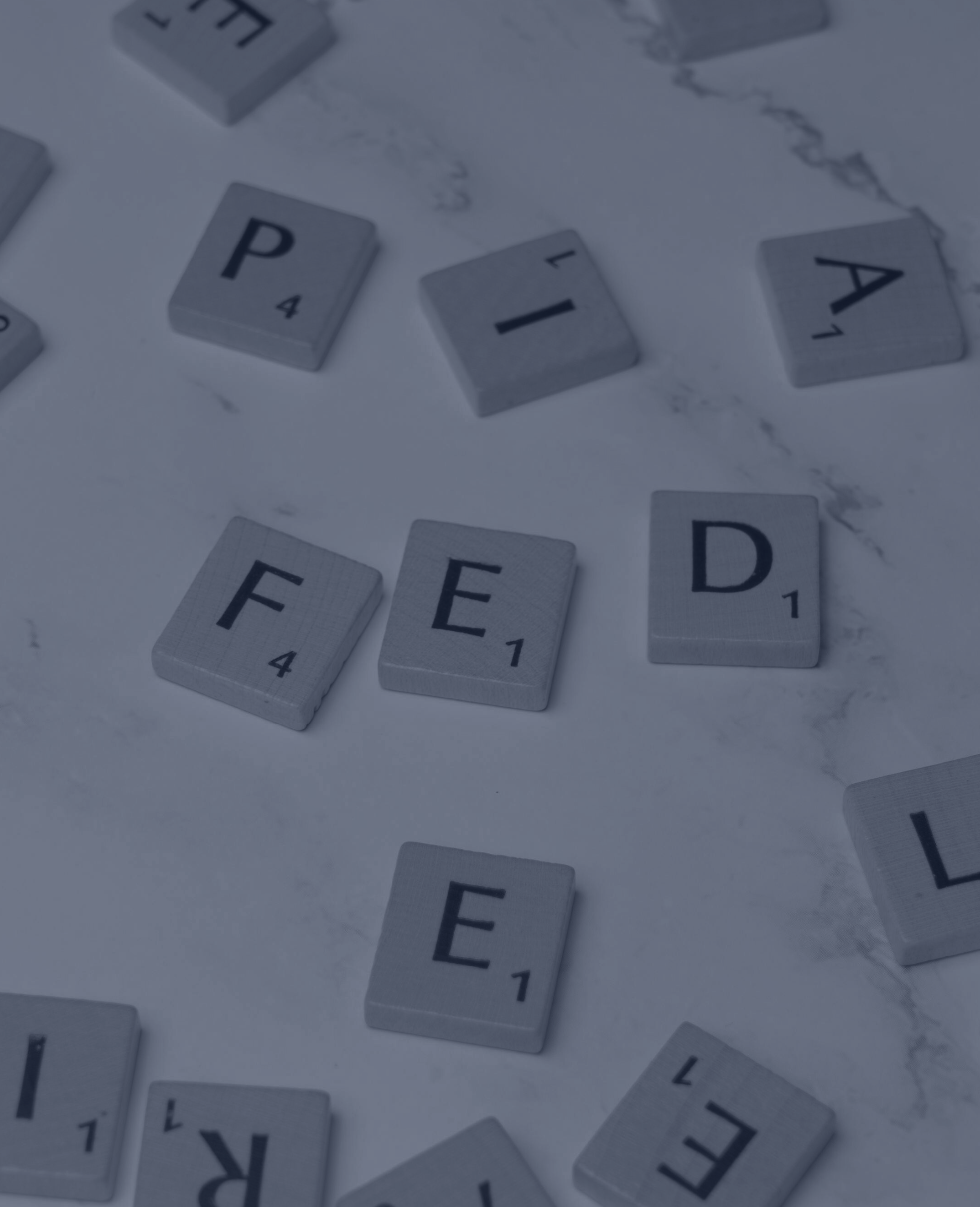Scrabble tiles scattered on a light-colored surface, displaying the words 'P I A E E' and some blank tiles.