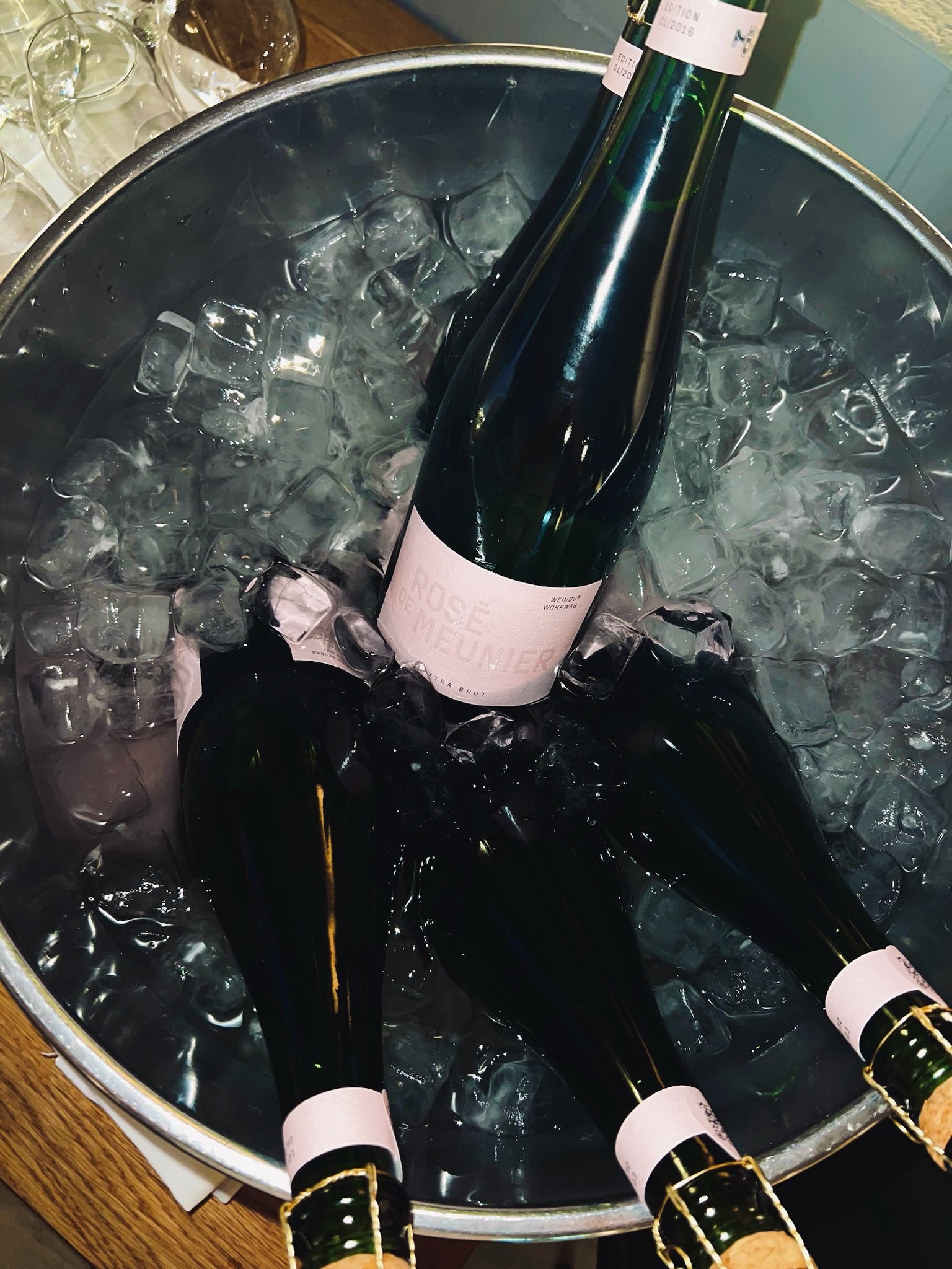 Four bottles of sparkling wine chilling in a large ice bucket.