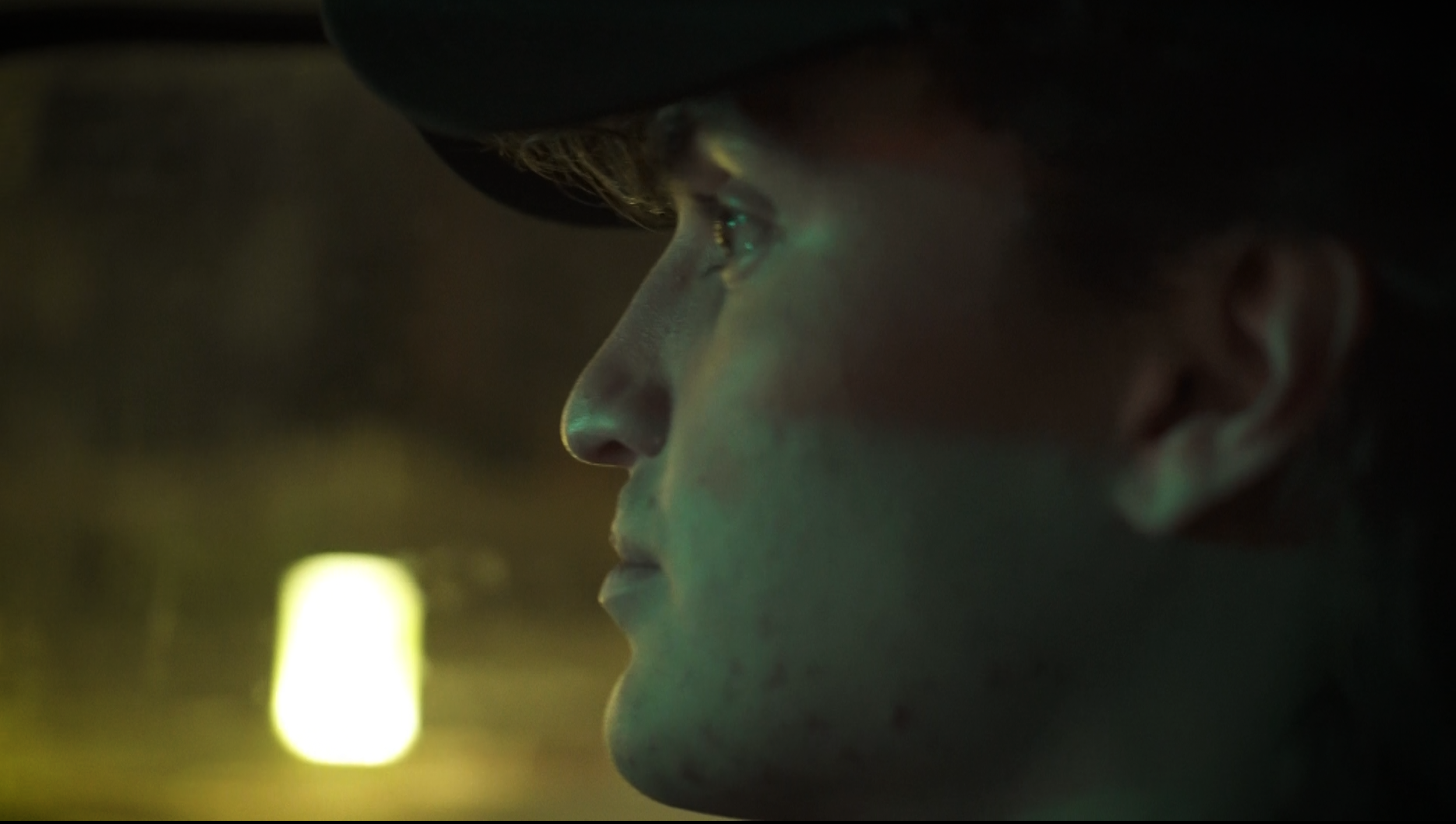 Close-up profile of a woman's face with her eyes looking serious, with a dark background and soft lighting highlighting her facial features.