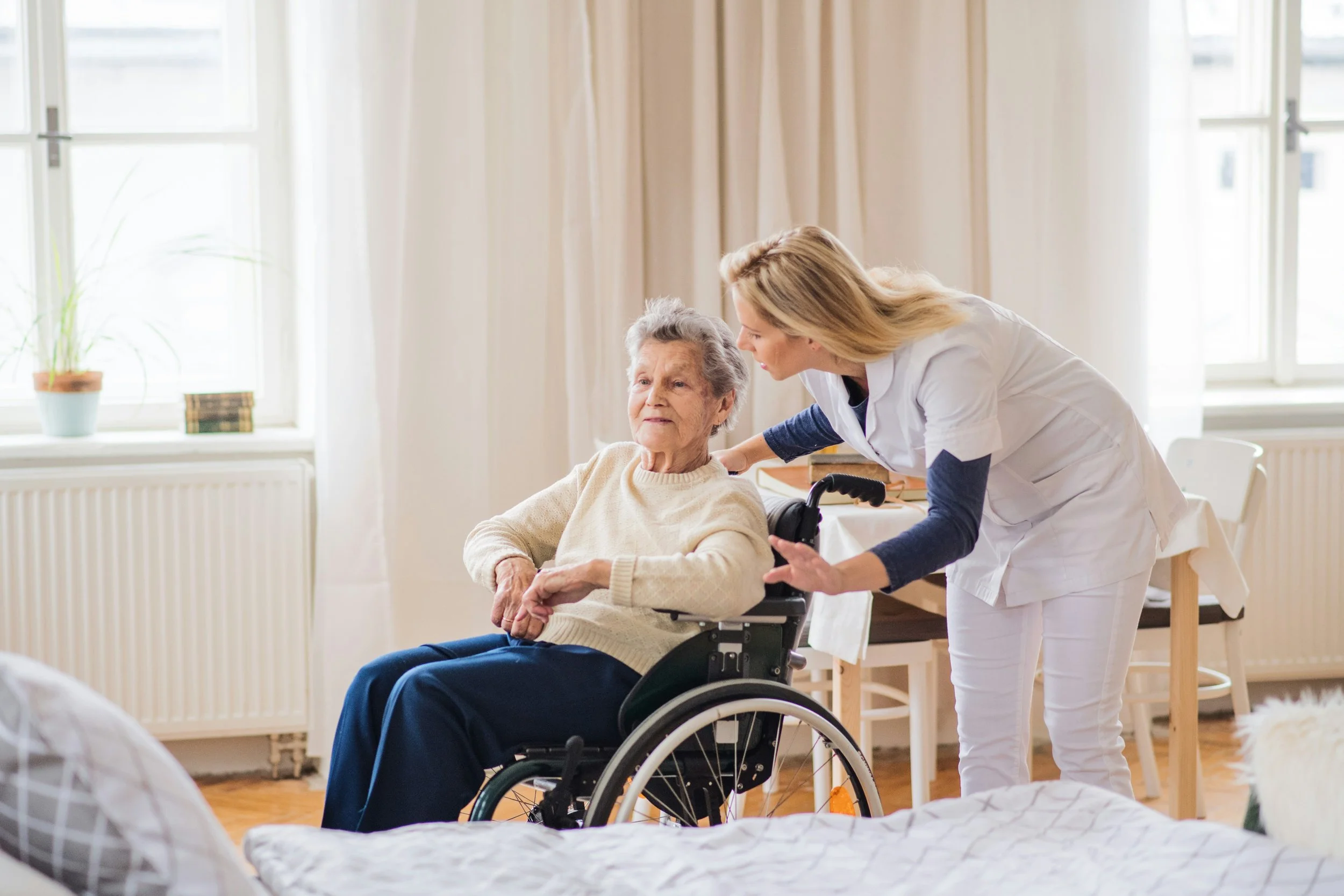 Home carer assisting an older woman with daily support and mobility care.