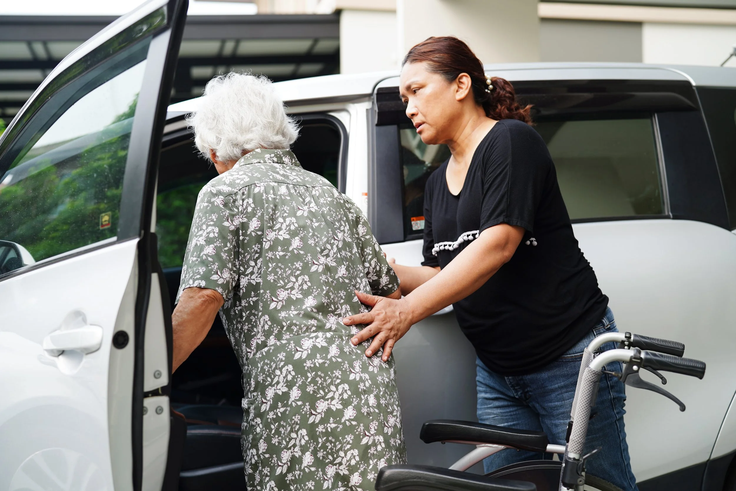 Carer assisting a client with safe transportation and mobility support.