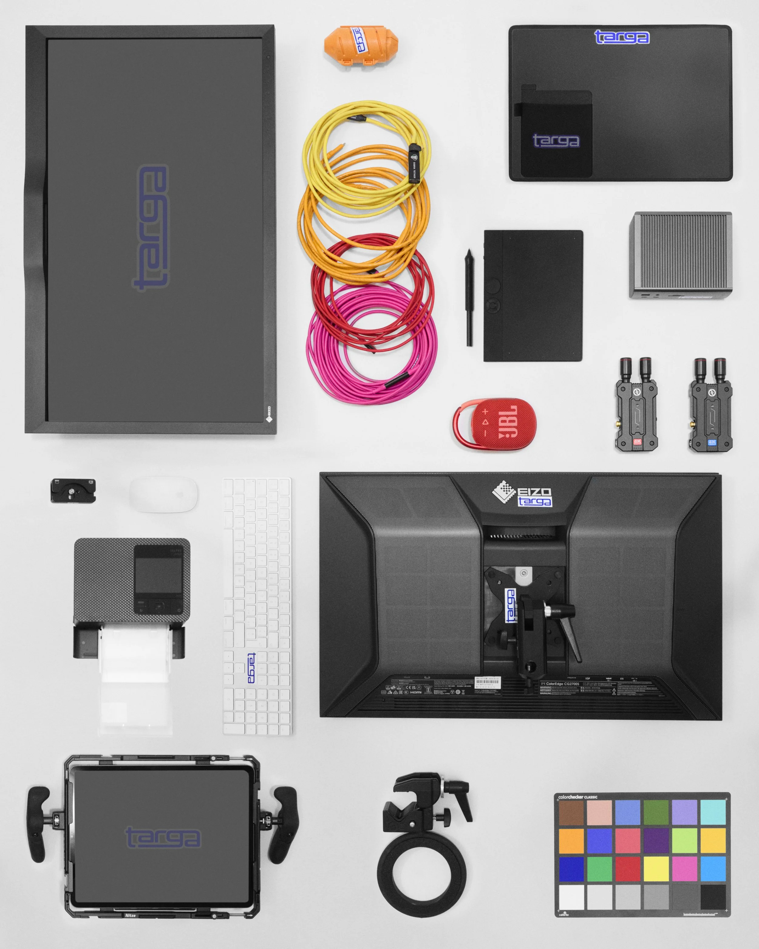 Disposizione di apparecchiature e accessori per il gaming e il lavoro da casa, tra cui monitor, tastiera, mouse, cavi colorati, altoparlanti, webcam, e altri dispositivi.