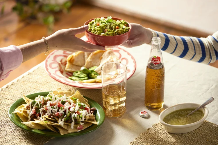 A shared table of nachos, guacamole and salsa