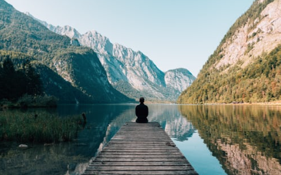 A person sitting sitting meditating in a mountain valley