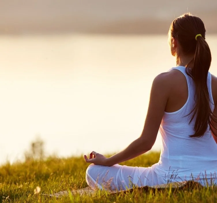 Woman meditating cross-legged on grass
