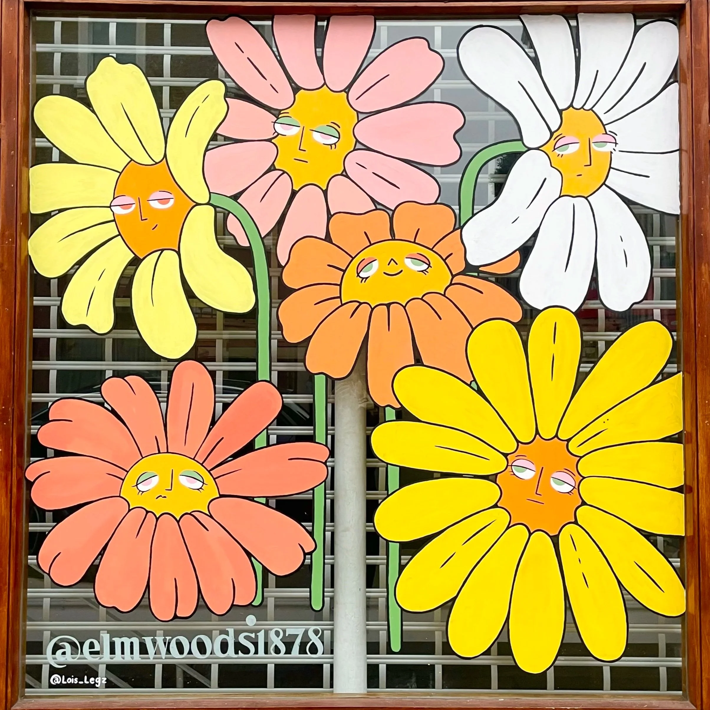 Colorful murals of large flowers with human-like faces, some with closed eyes and slight smiles, in pink, yellow, white, and orange colors, painted on a window with a wooden frame.