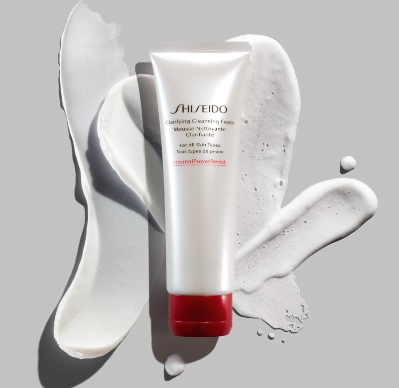 Shiseido Clarifying Cleansing Foam tube with white foam and cream splashes on a light gray background.