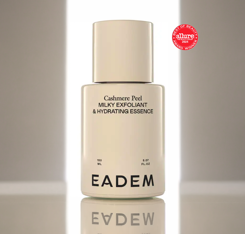 A white bottle of Eadem Cashmere Peel Milky Exfoliant & Hydrating Essence with a silver cap, on a reflective surface with a blurred background. A red Allure Best of Beauty 2024 award badge is in the top right corner.