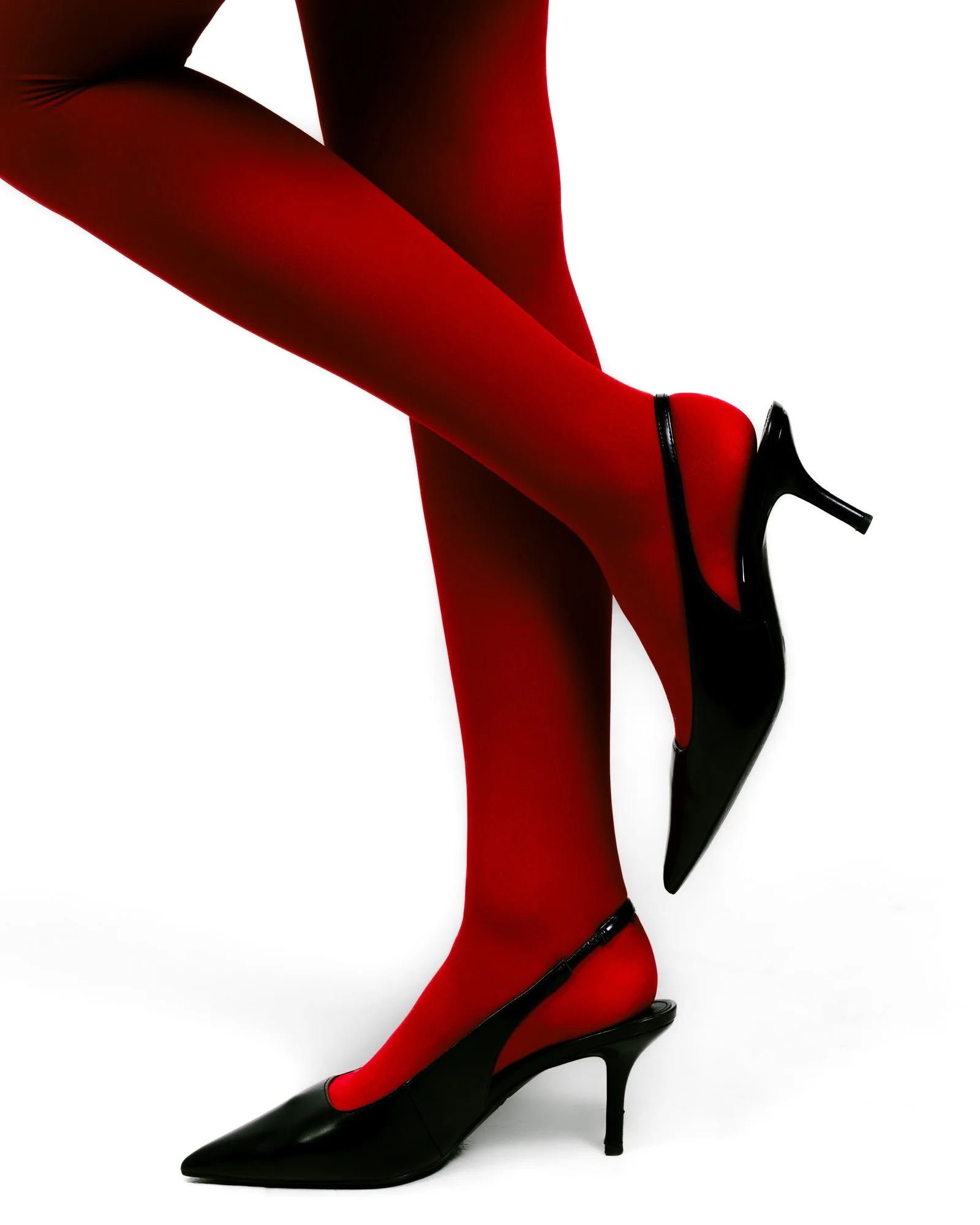 A person wearing red tights and black high heels, with one foot crossed over the other.