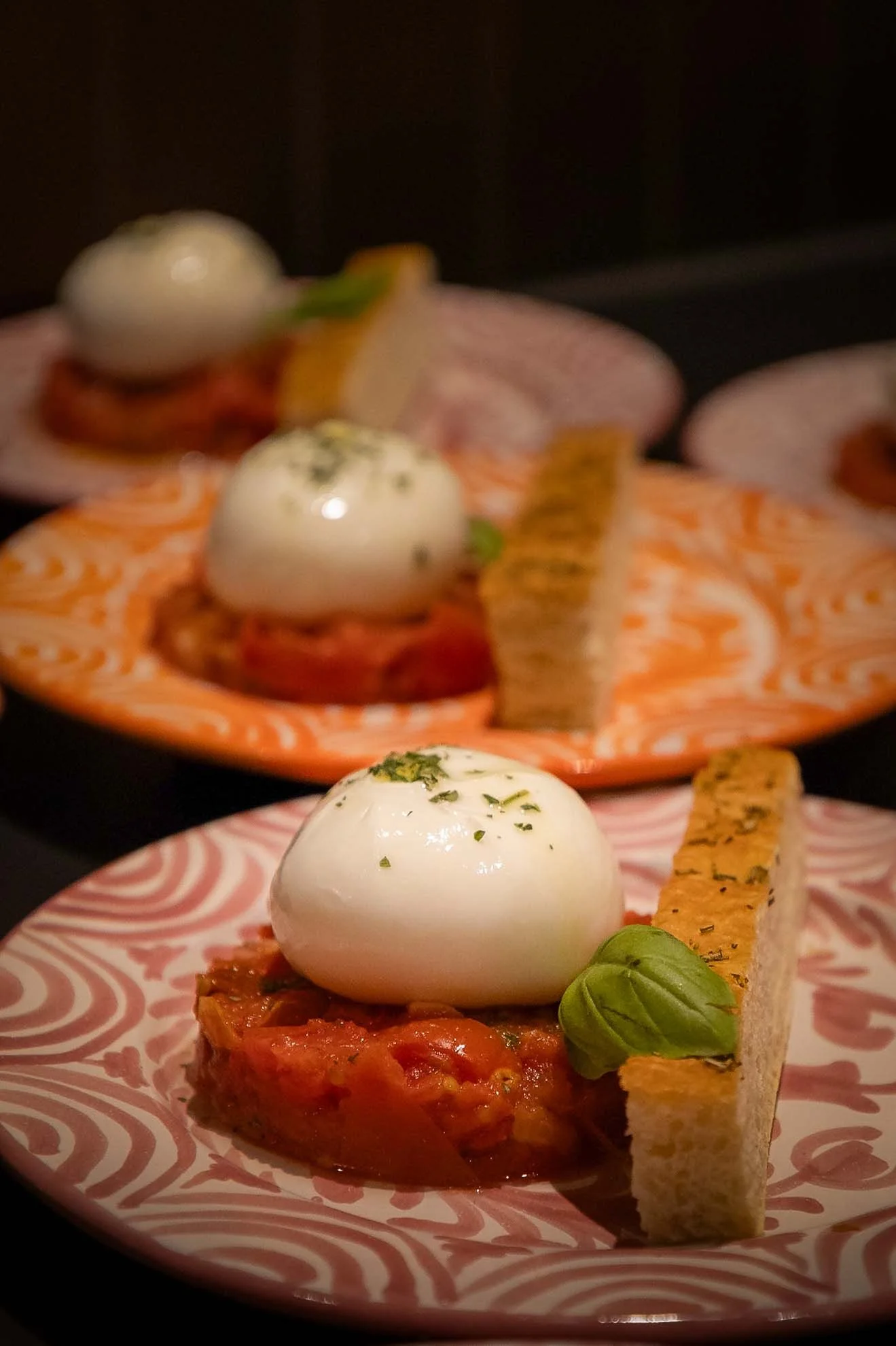 Gerecht met een gebakken tomatenbasis, een gepocheerd ei, basilicum, en een krokante toast op een oranje en witte gestreepte kom.
