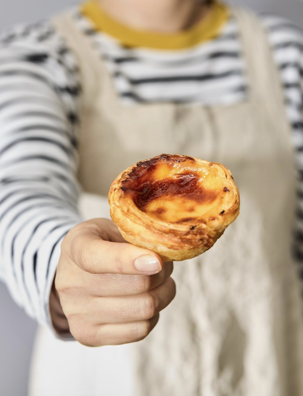 Person holding a Portuguese custard tart with caramelized top