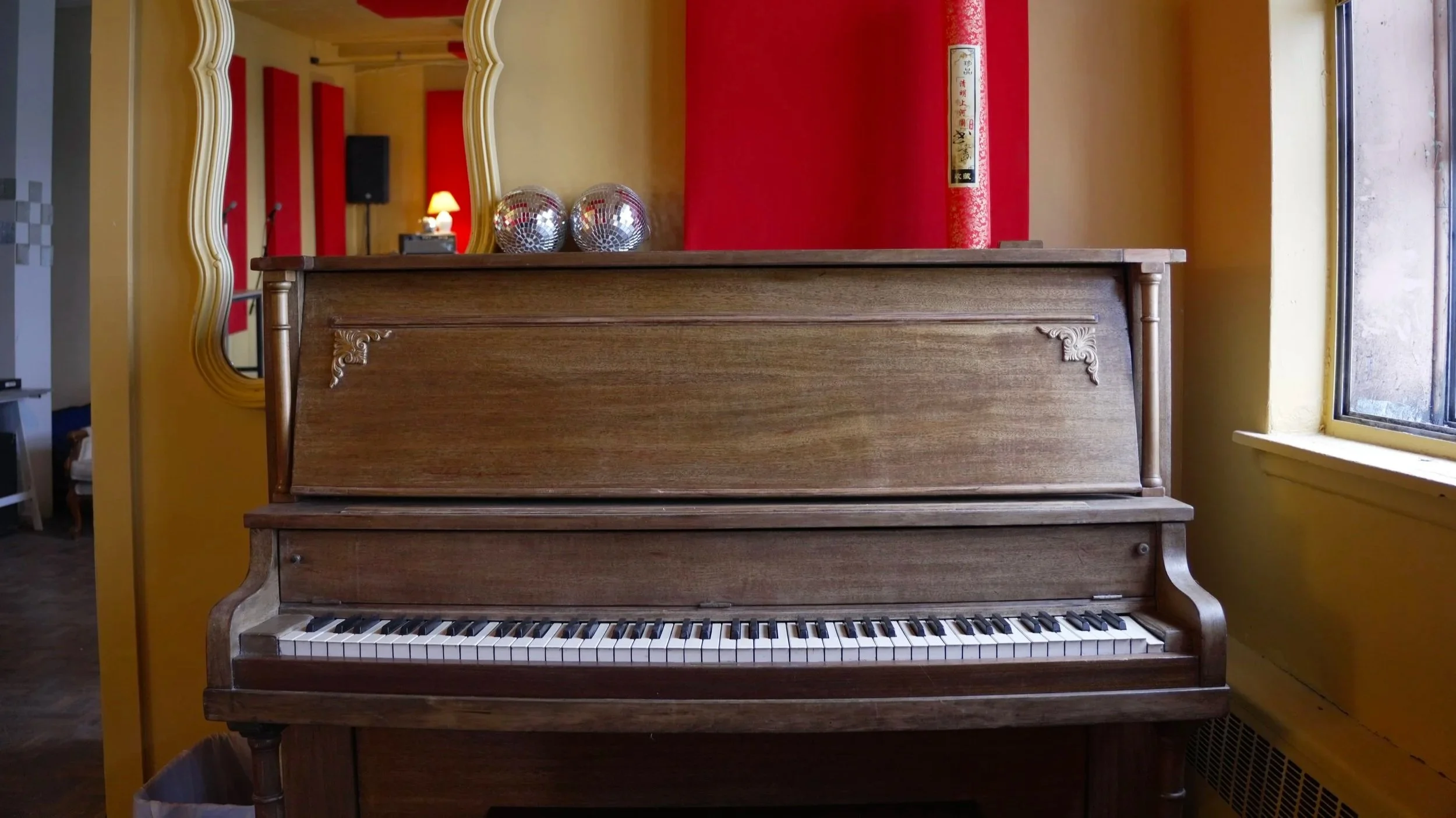 Microphone installé dans un studio de musique avec batteries, amplificateurs, une lampe de table et des panneaux acoustiques.