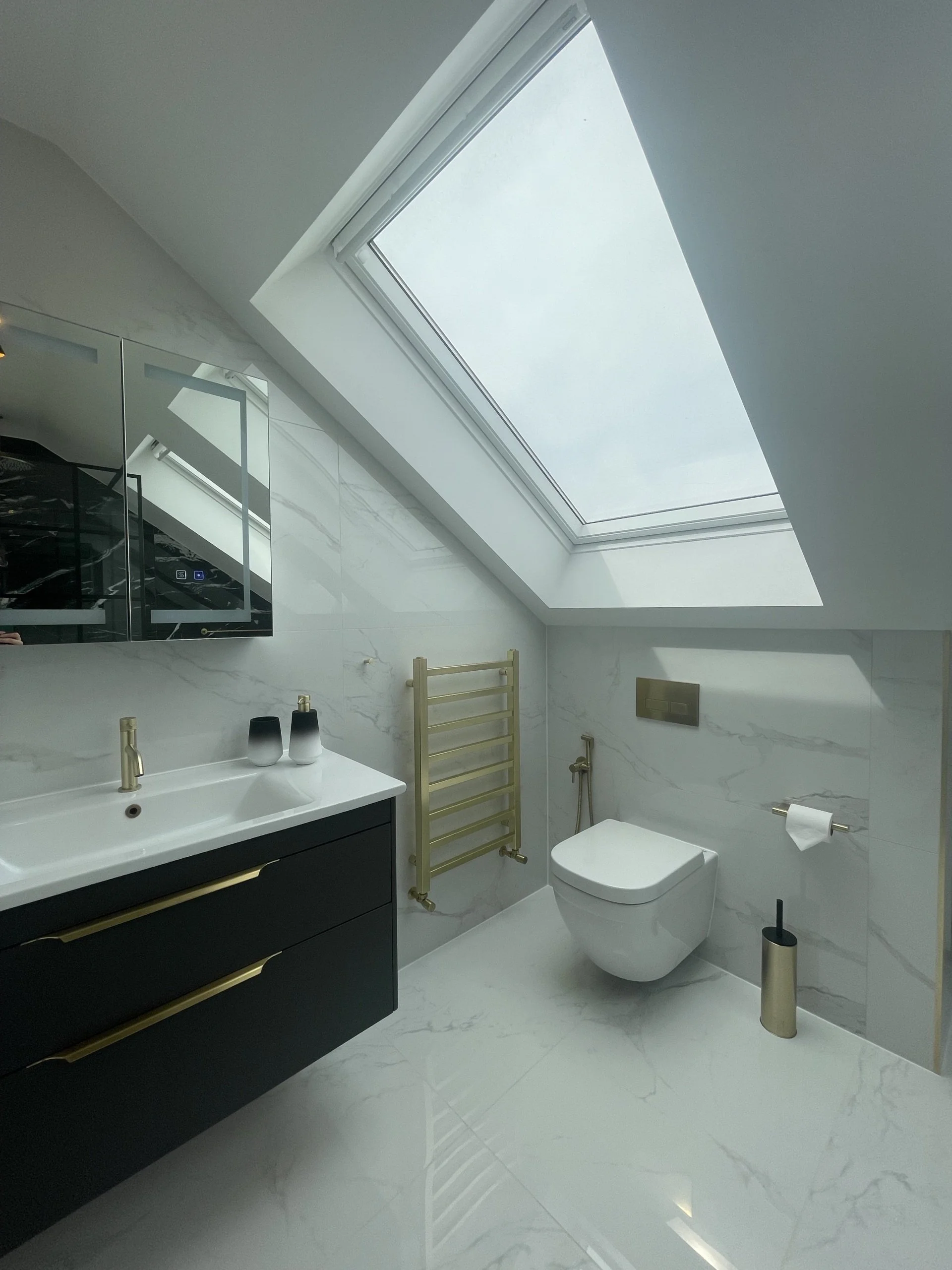 En suite shower room in a RELM loft conversion with roof light and brass fittings