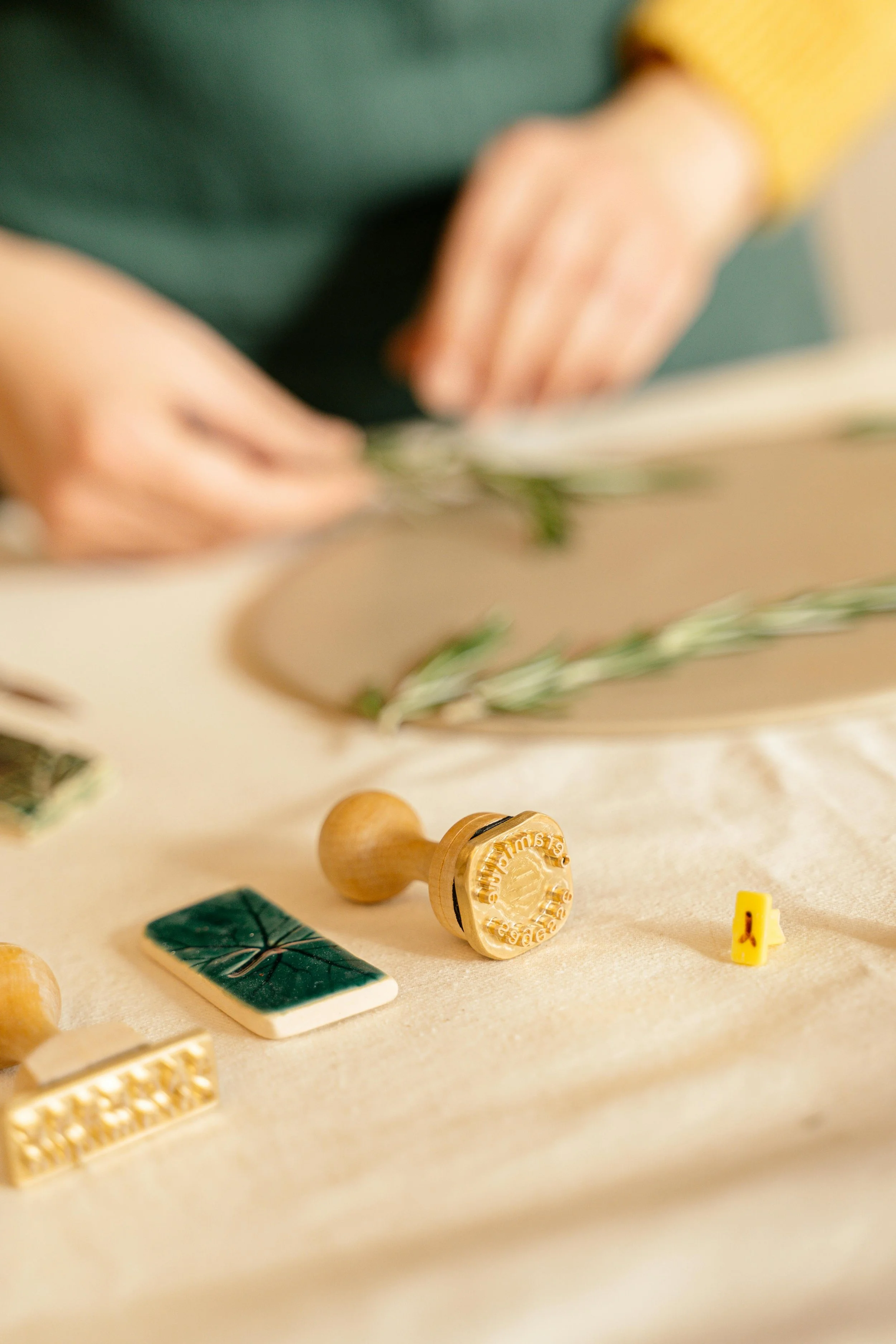 Une personne utilisant un tampon encreur parmi d'autres tampons et accessoires sur une surface beige.