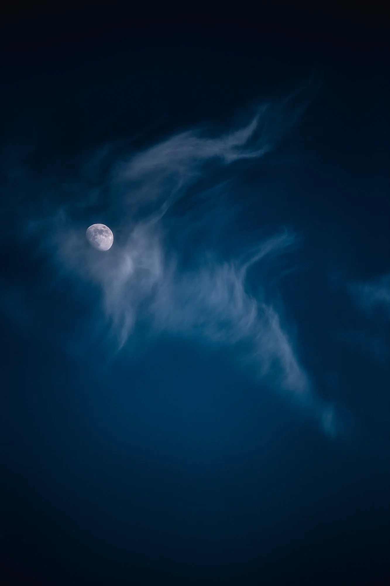 Night sky with visible moon and wispy clouds.