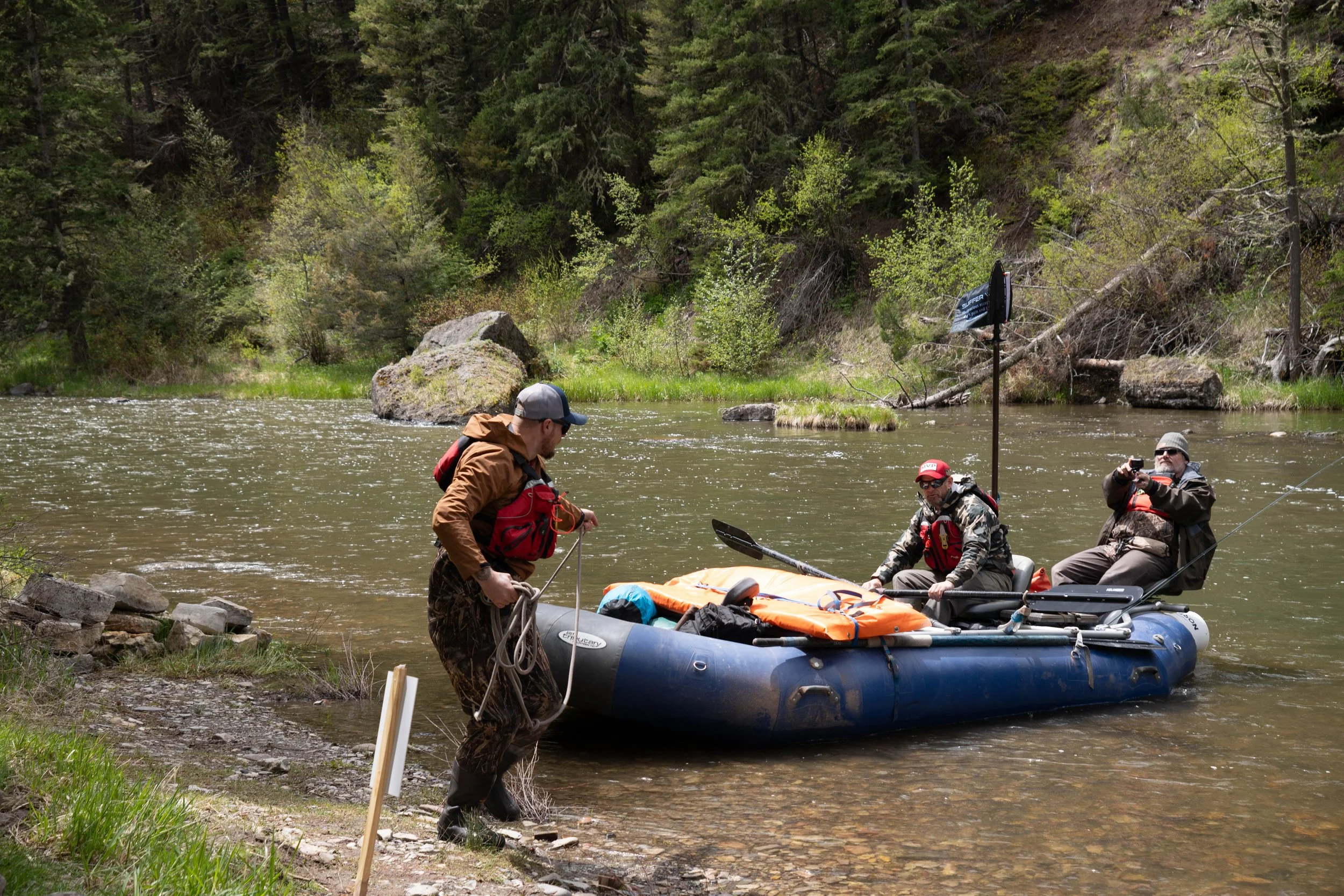 veterans floating the smith river. one veteran is pulling a raft with two veterans to shore