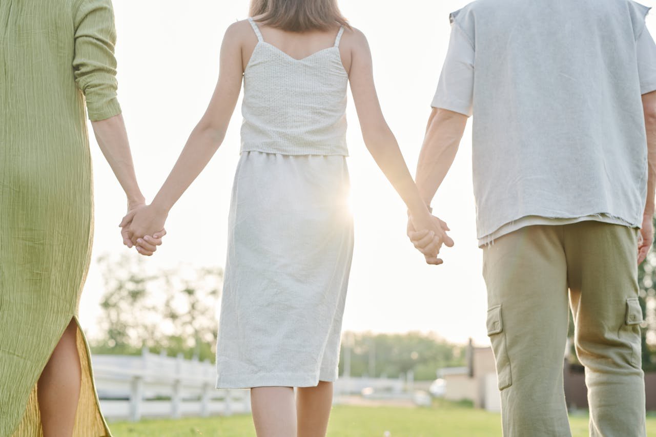 Una famiglia di spalle cammina all'aperto tenendosi per mano.