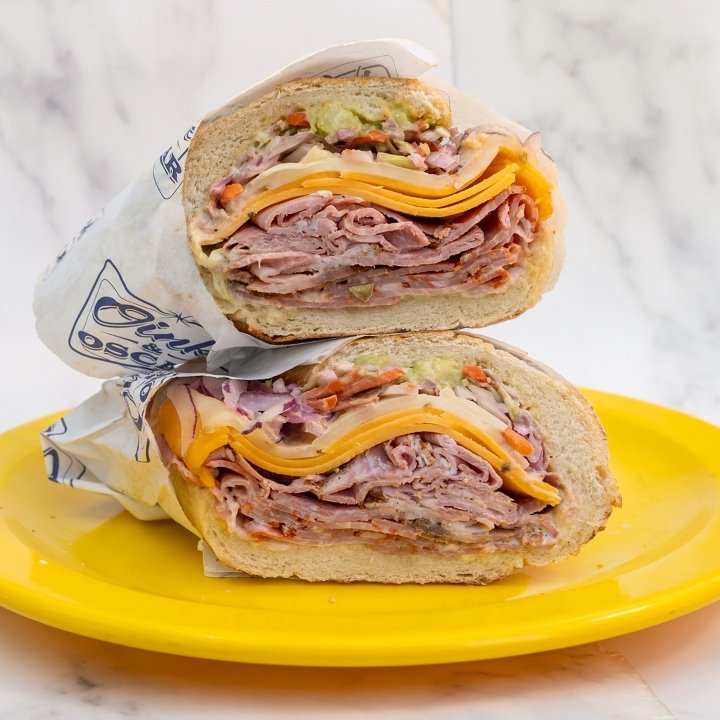 Halved sandwich with sliced turkey, cheddar cheese, lettuce, and tomato, Oink & Oscar