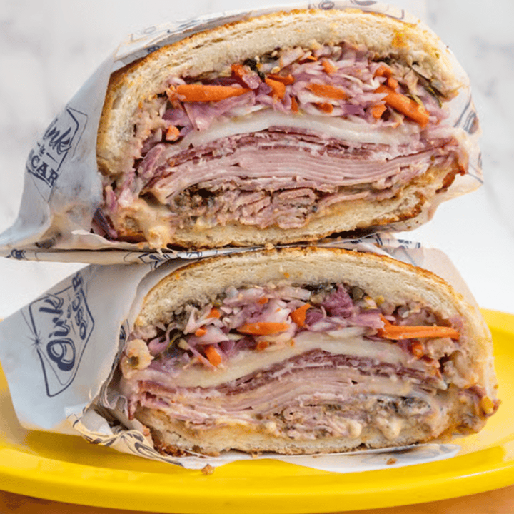 Cross-section of a sandwich with layers of ham, turkey, cheese, pickles, and bread.