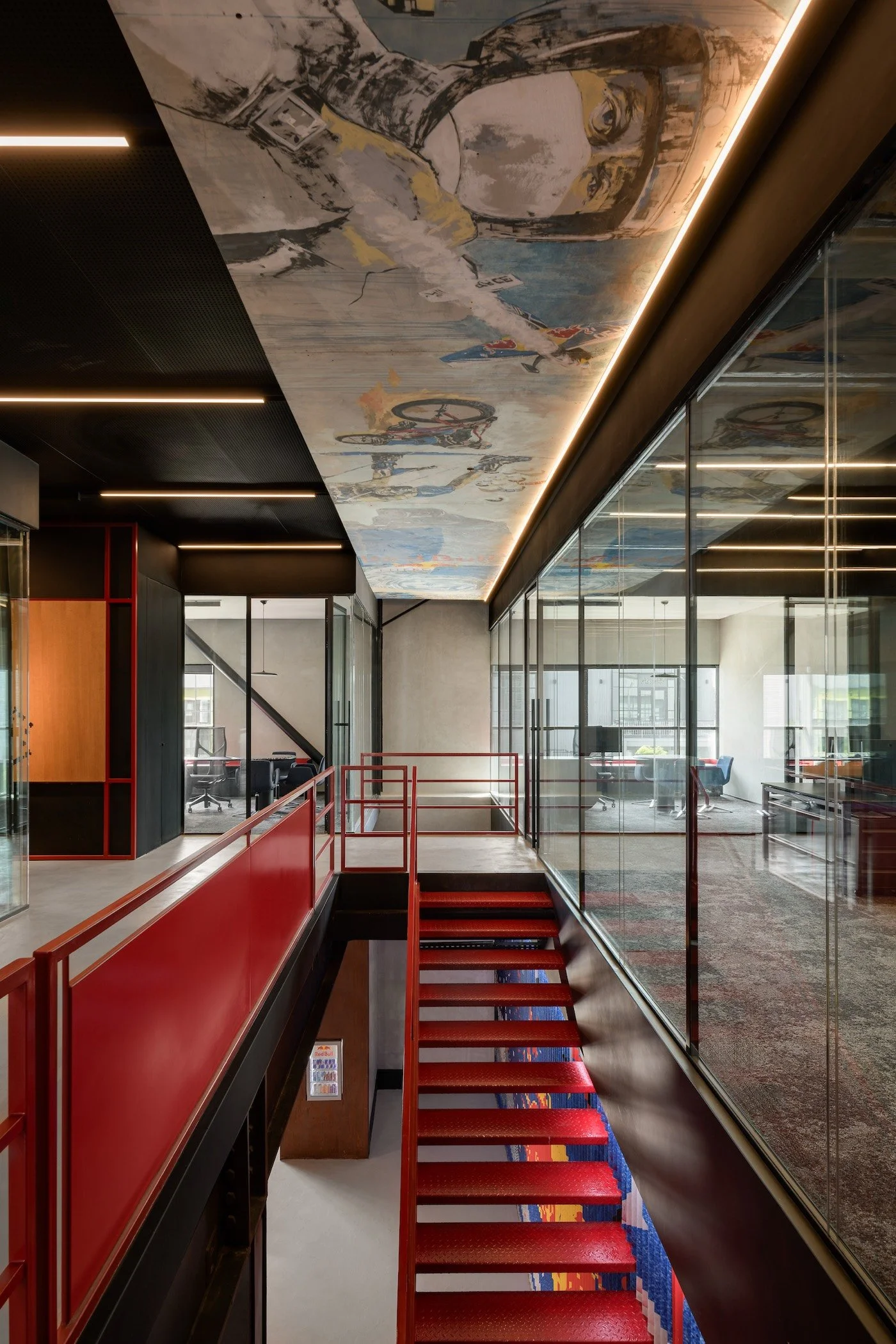 Ceiling mural by Aya Tarek at Red Bull Cairo headquarters, 2018 — figurative painting spanning the office ceiling above a red staircase. Photography by Nour El Refai