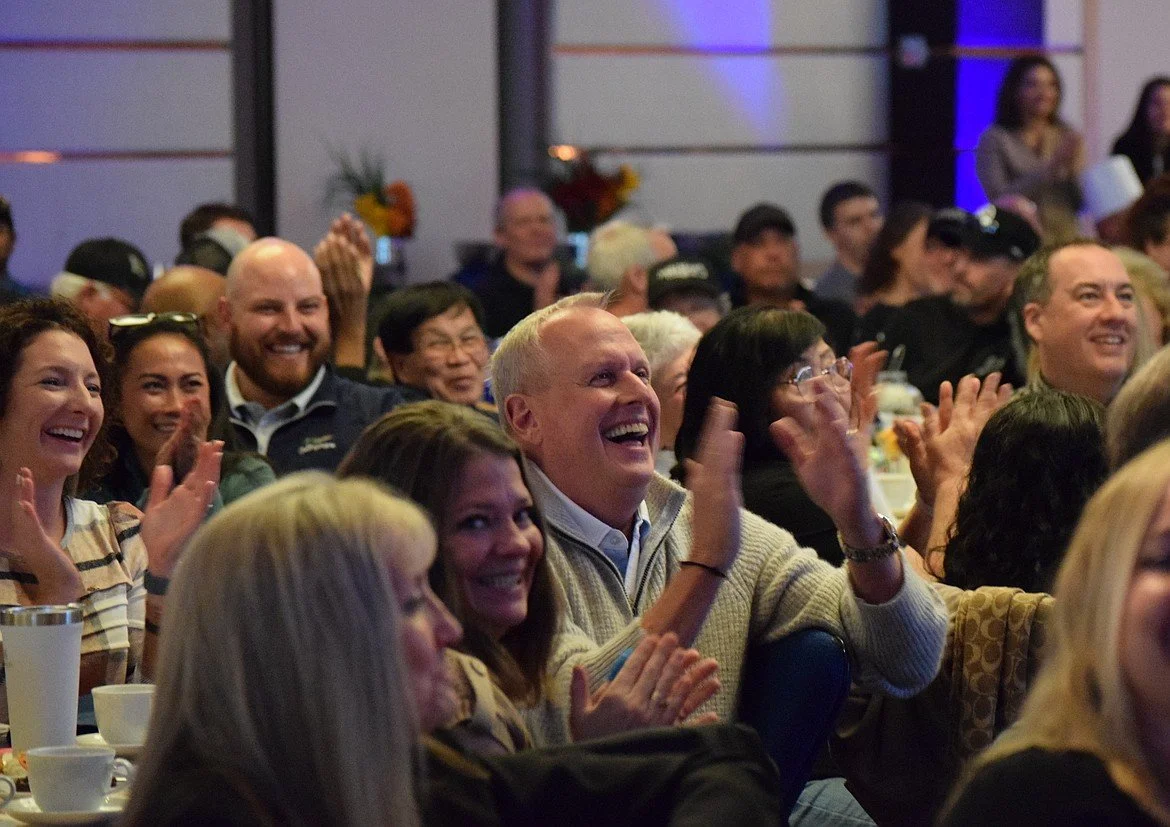 Audience at an event laughing and clapping.