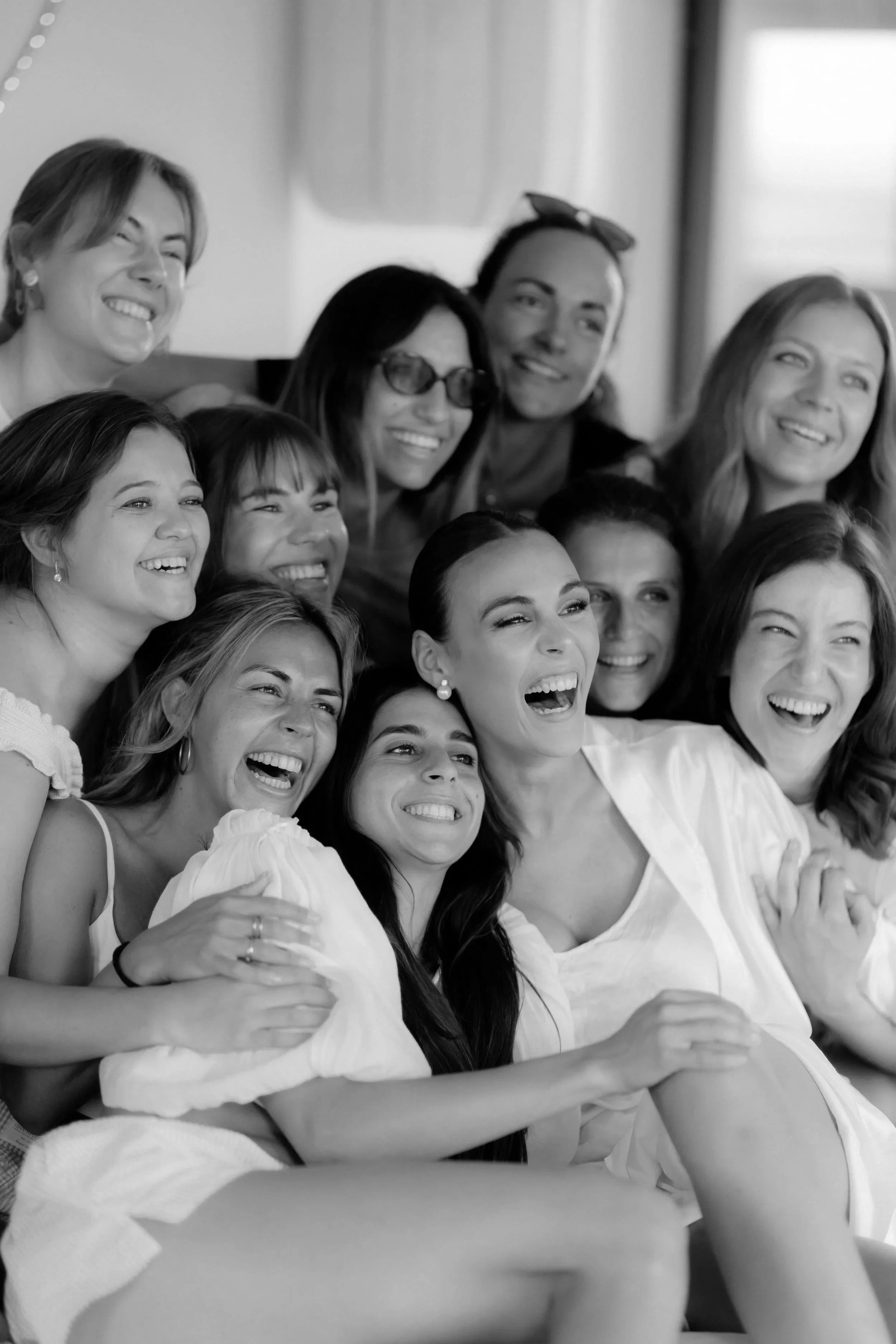 Eine Gruppe lachender Frauen, die eng zusammen in einem Raum stehen, beim gemeinsamen Ausflug oder Treffen.
