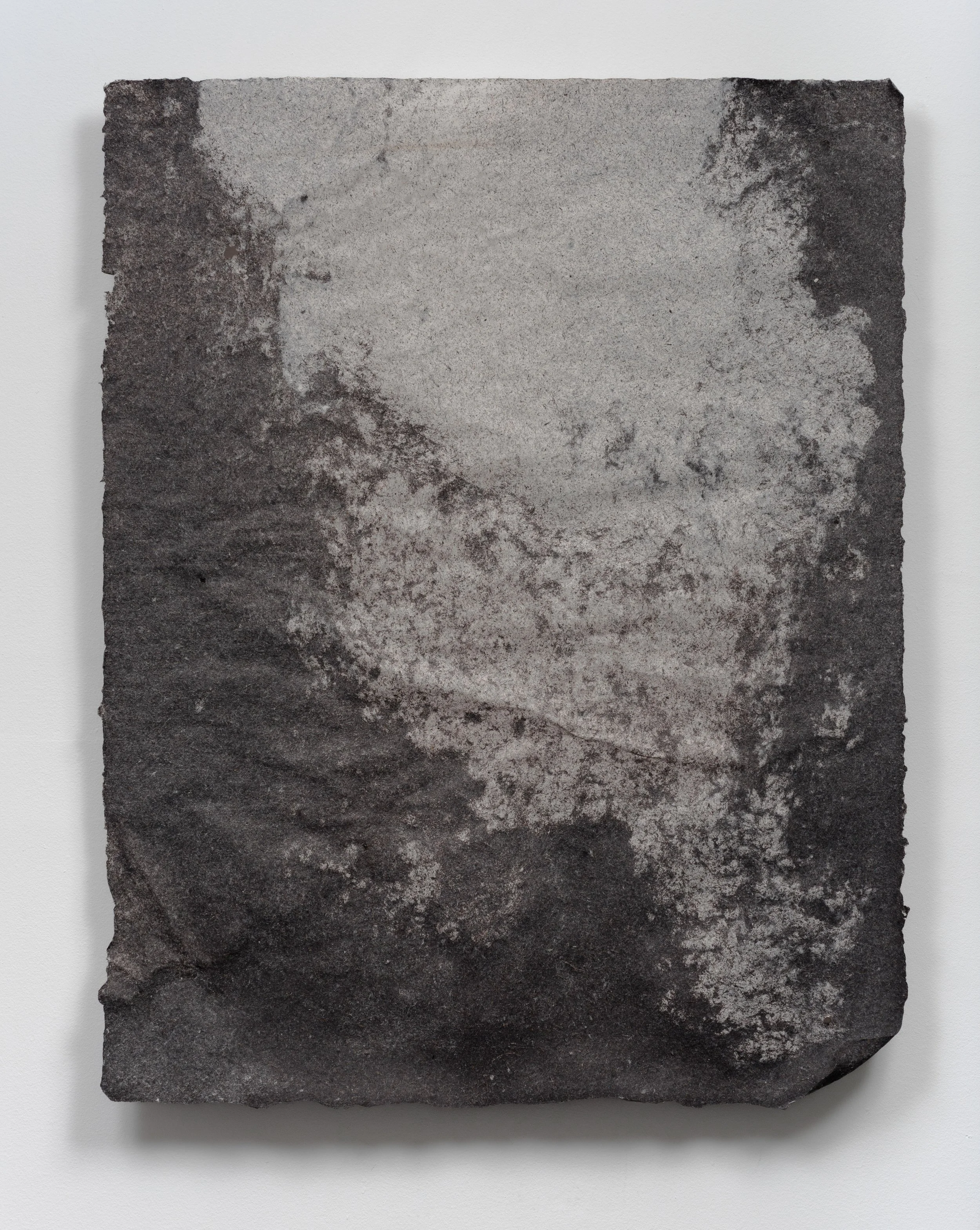 A black and white photograph of a textured, weathered rectangular stone or concrete slab with rough edges, mounted on a white background.