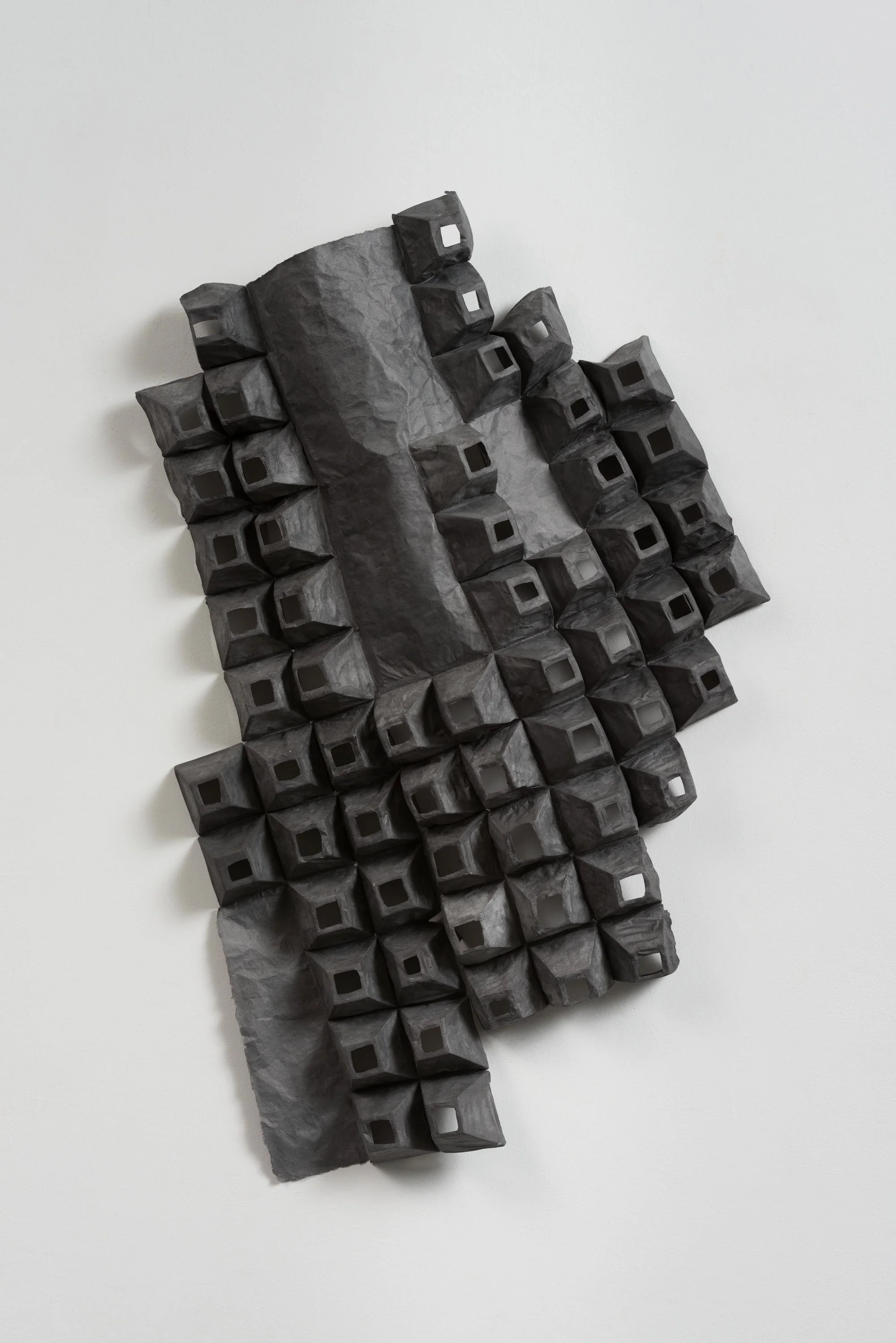 Contemporary black and gray abstract sculpture with geometric cubic shapes mounted on a white wall.
