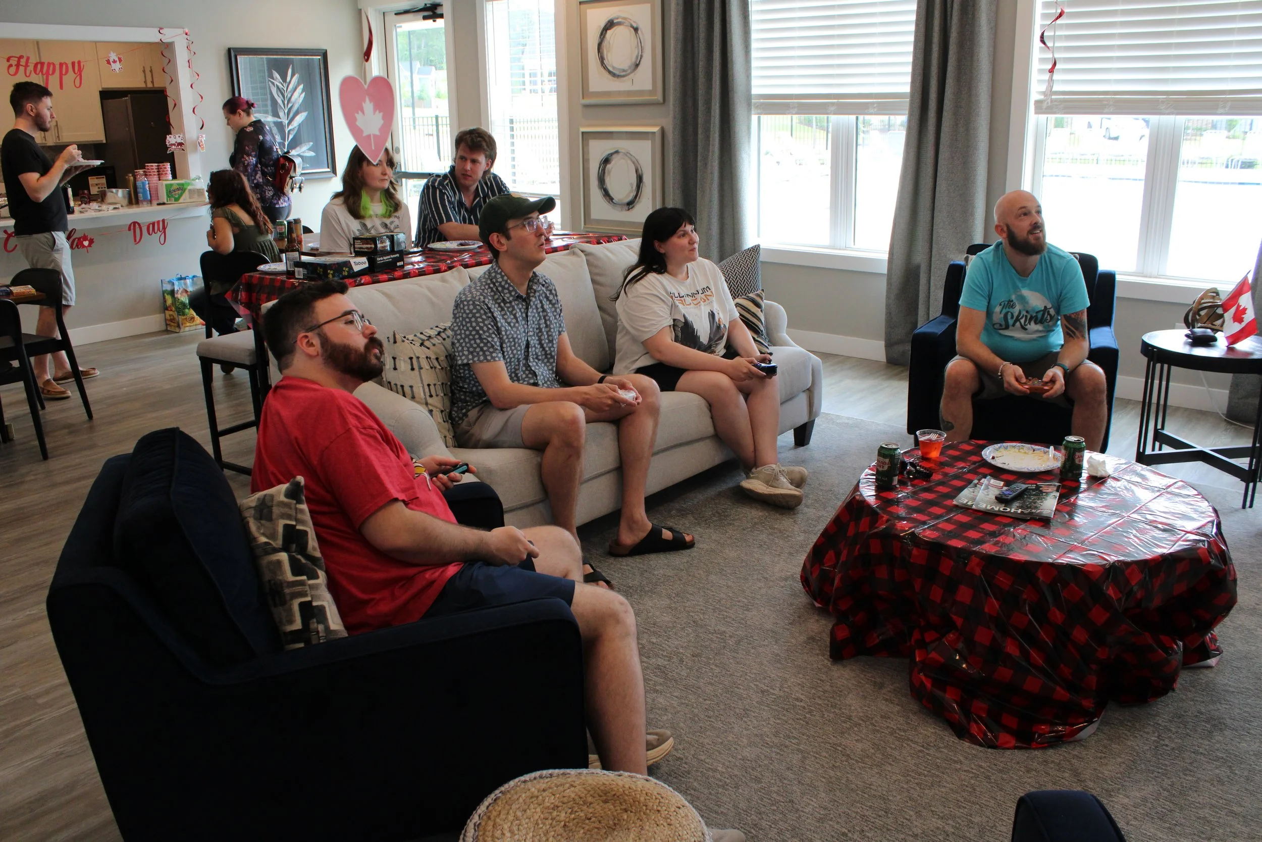 Triangle QuestHouse members playing video games at the Canada Day party with red and white decorations