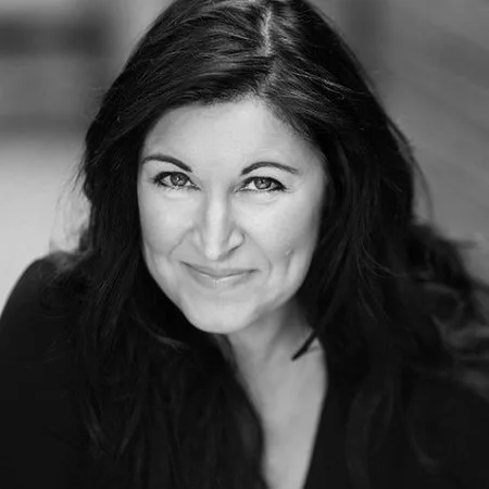 Black and white portrait of a woman with long dark hair, smiling and looking at the camera.