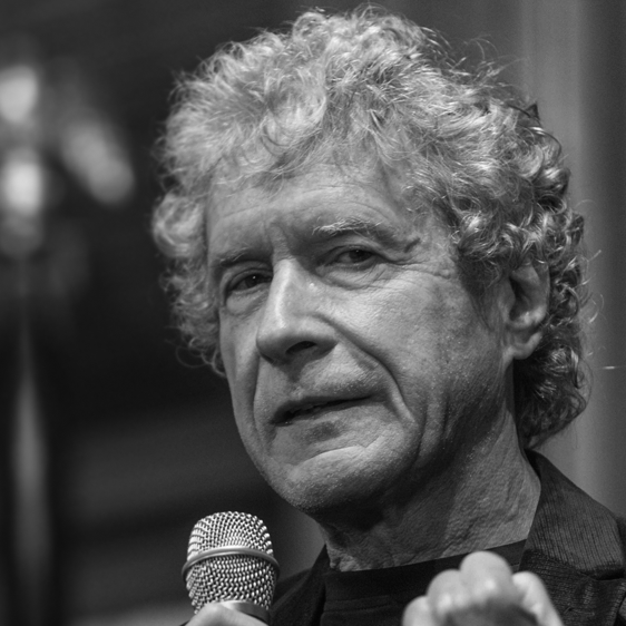 Black and white photo of a man with curly gray hair holding a microphone