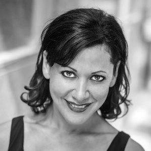 Black and white photo of a woman with dark, shoulder-length hair smiling at the camera.