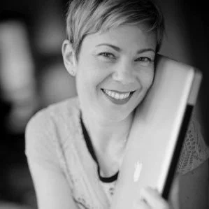 A woman smiling while holding a laptop.