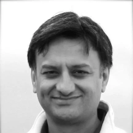 Black and white photo of a smiling man with short dark hair