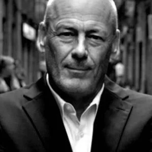 Black-and-white portrait of a bald man in a suit on a city street
