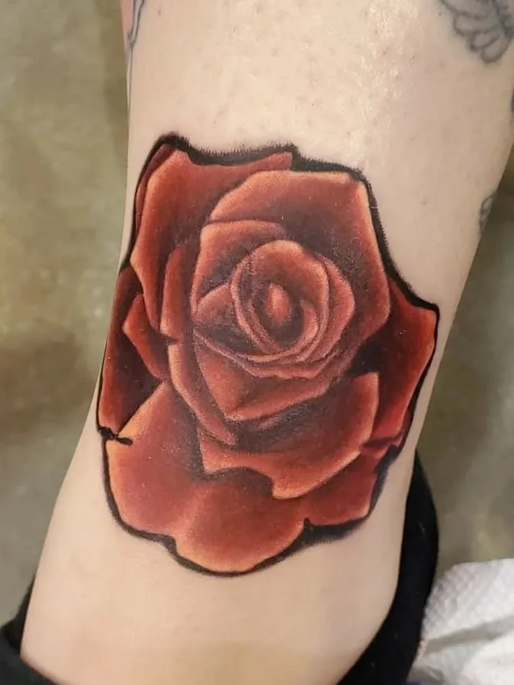 Tattoo of a realistic red rose on a person's arm.