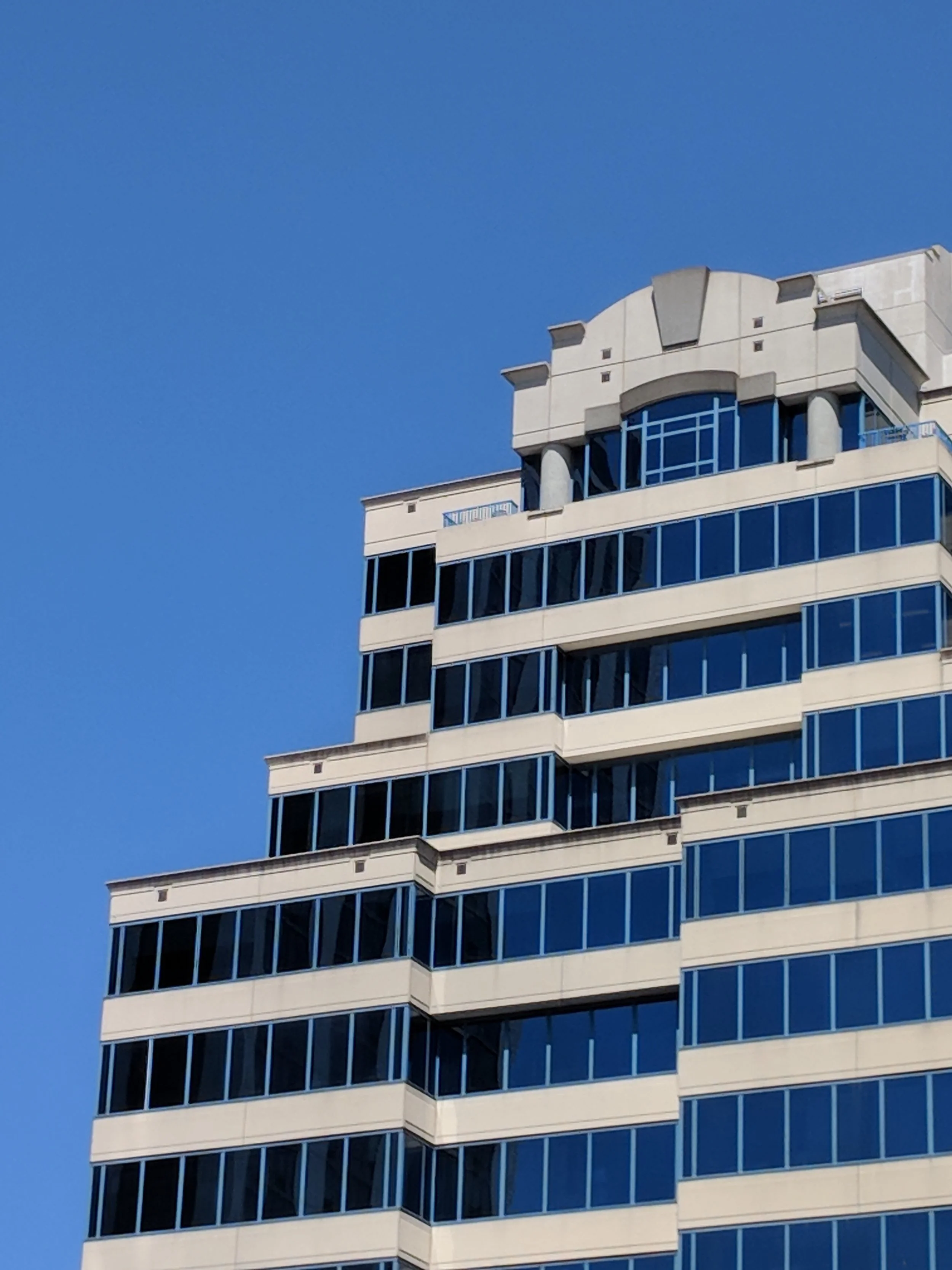 Close-up of a modern skyscraper with blue-tinted glass windows against a clear blue sky.