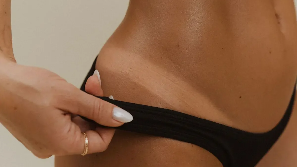 Close-up of a person pulling down black underwear to reveal skin.