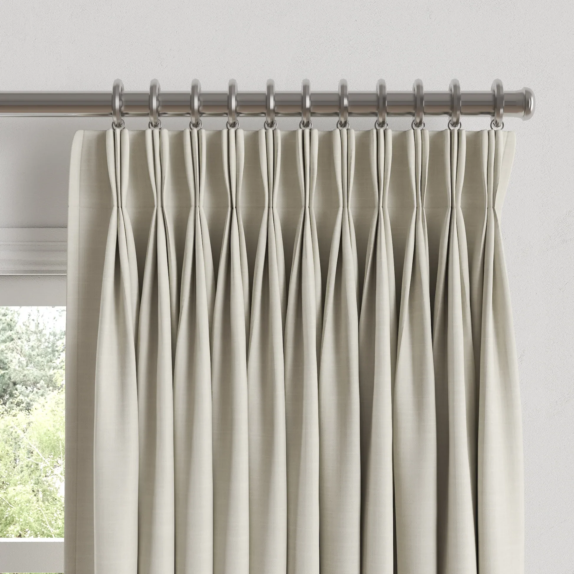 Cream-colored curtains hanging on a silver curtain rod in front of a window with a view of trees outside.