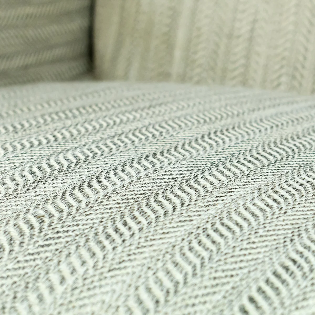 Close-up of a textured, patterned fabric on a sofa with cushions in the background.