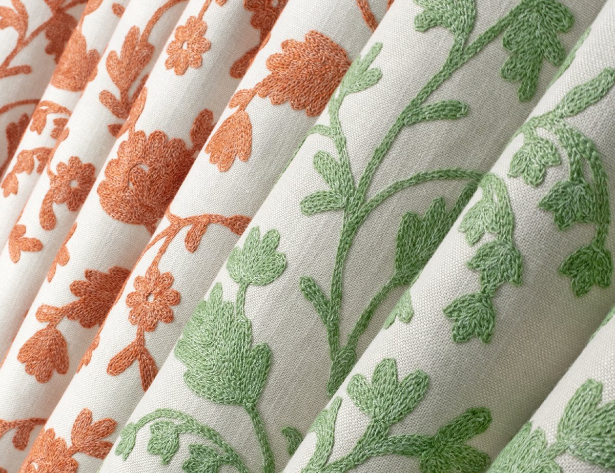 Close-up of embroidered fabric with orange and green floral patterns.