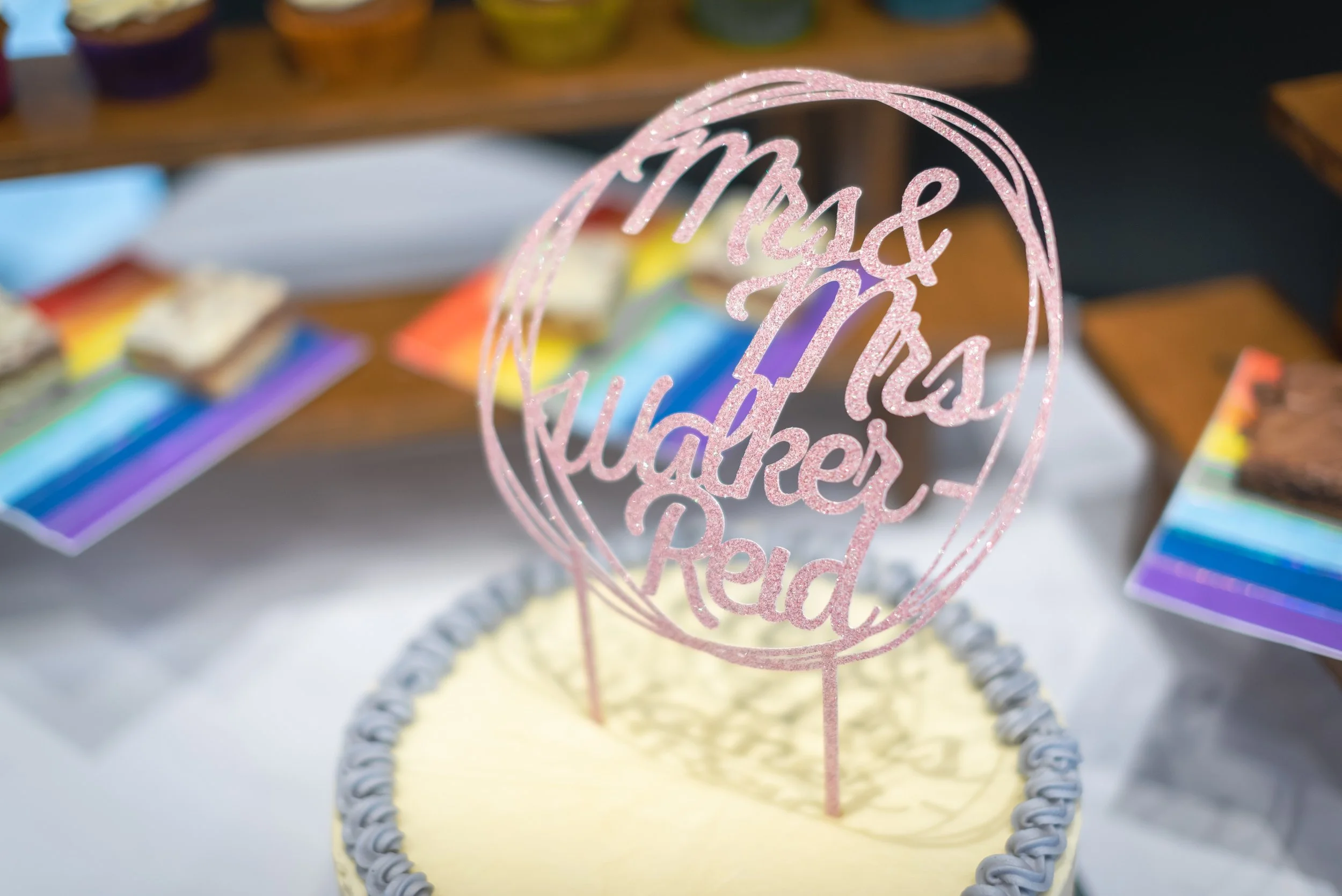 Close-up of a birthday cake with a pink glittery topper during a Cotswolds wedding