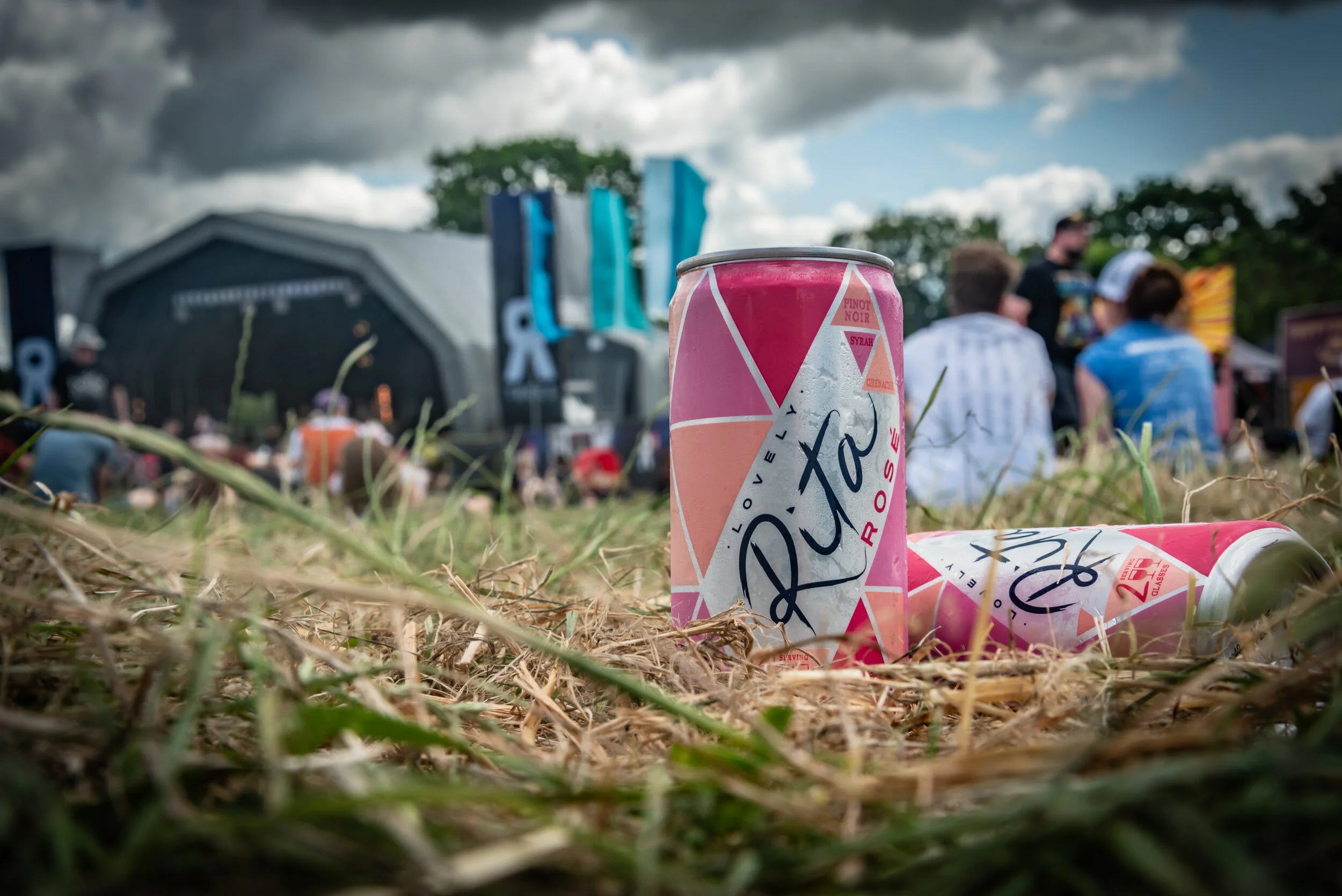 Product photography of canned wine at a rock festival in a field