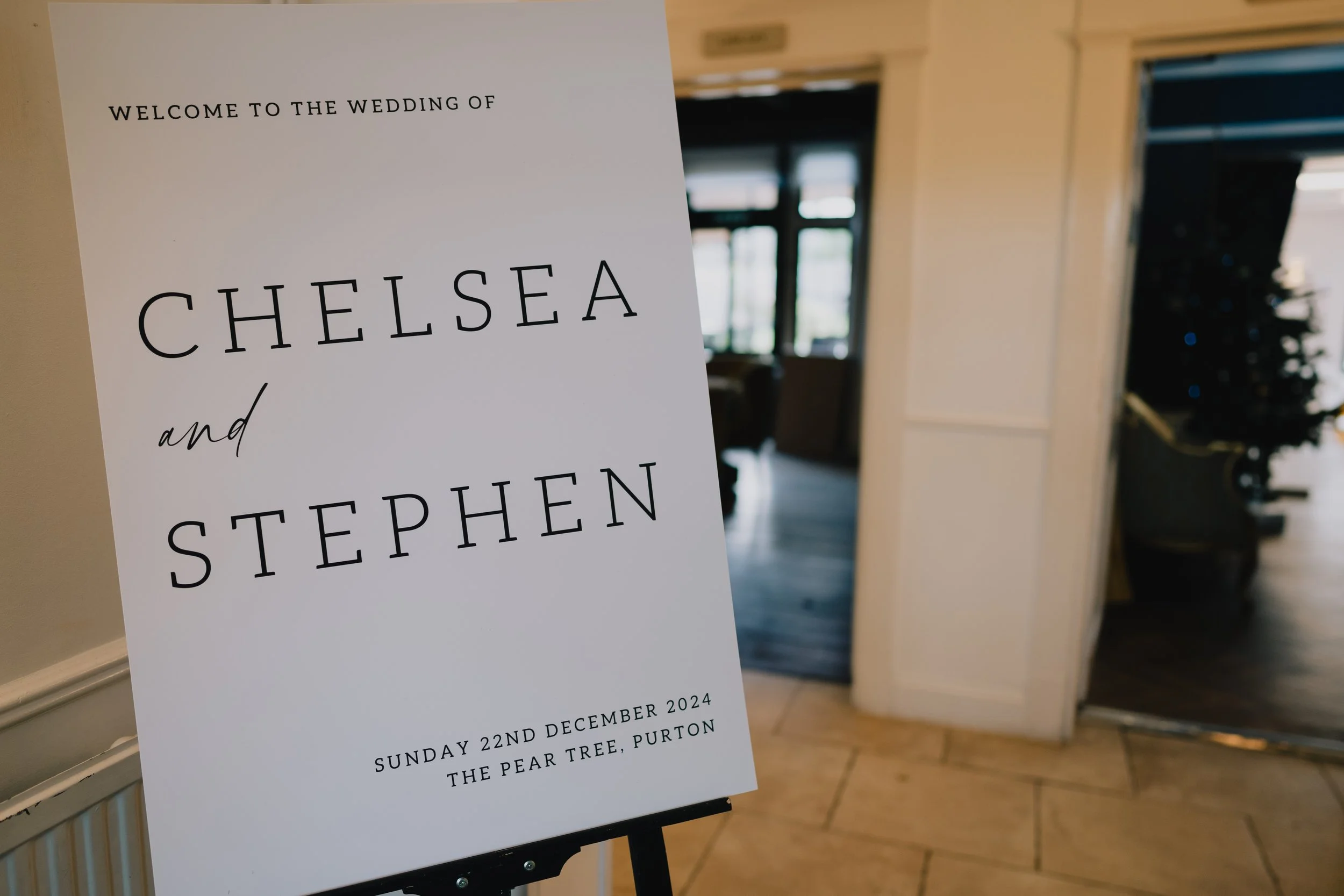 Classic welcome sign inside The Pear Tree, Purton, greeting wedding guests with elegant floral styling and countryside charm.