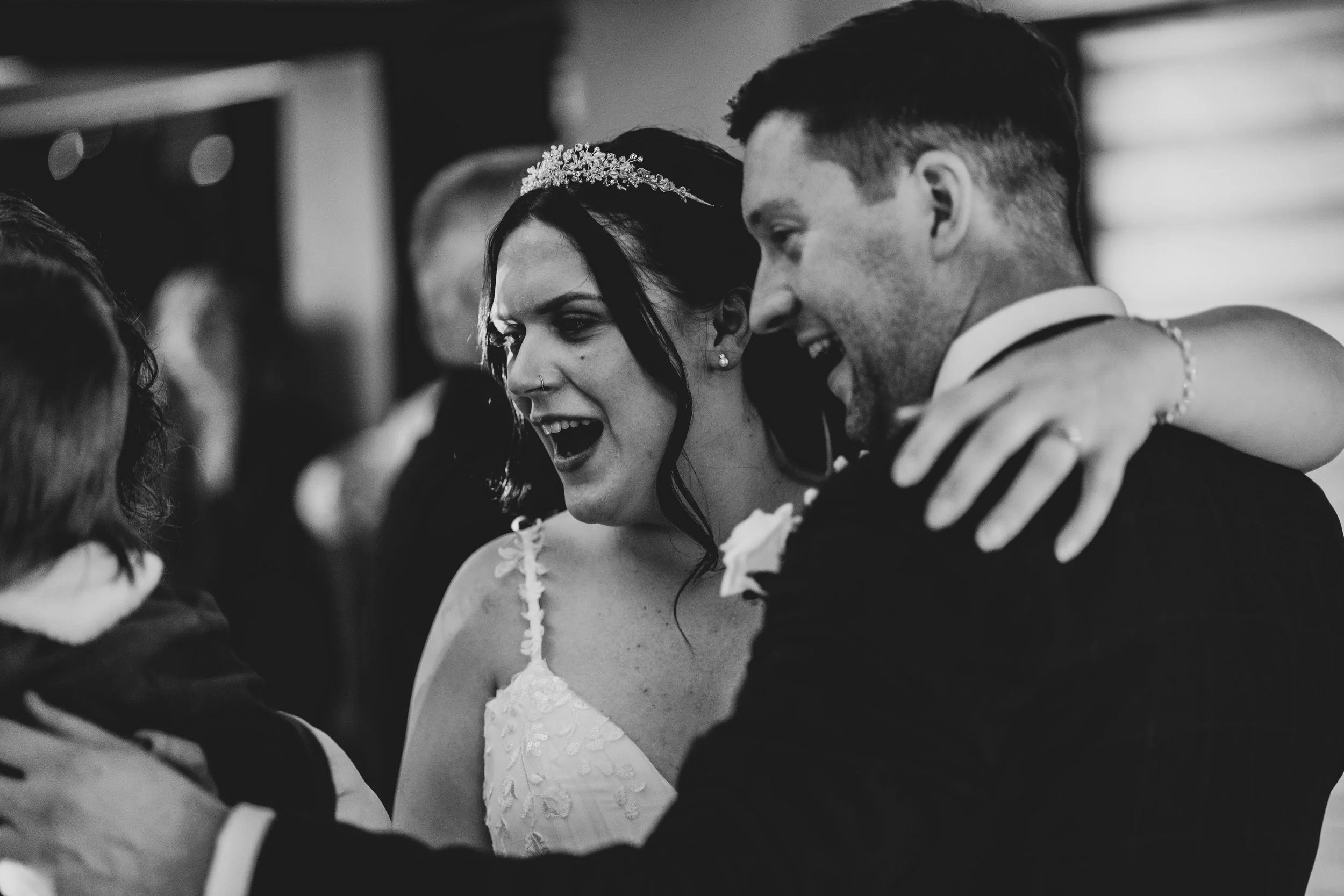 Black and white photo of a bride and groom smiling and hugging during their first dance at Pear Tree captured by Pear Tree wedding photographer