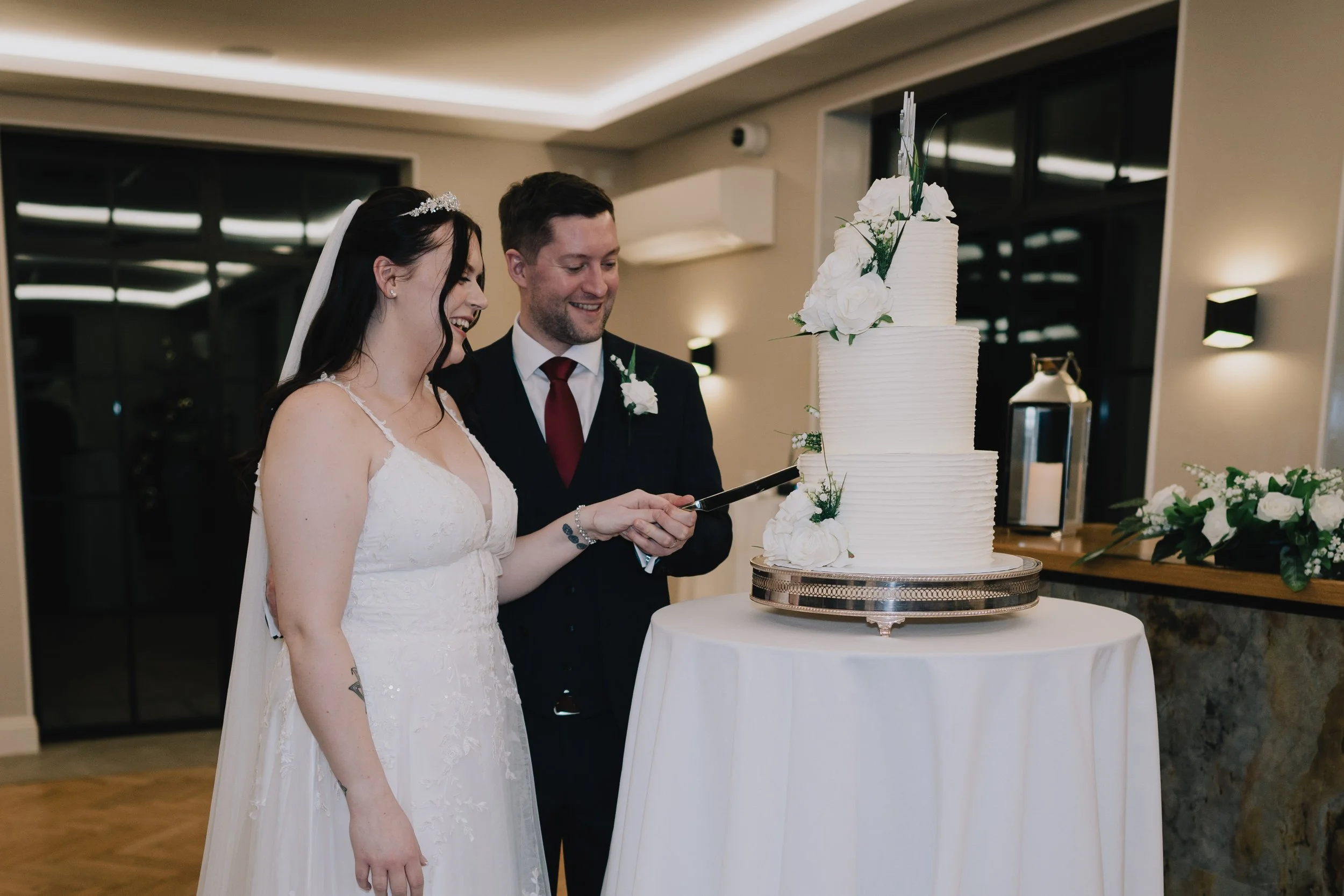 A bride and groom cutting a wedding cake together in a decorated reception area at Pear Tree in Purton