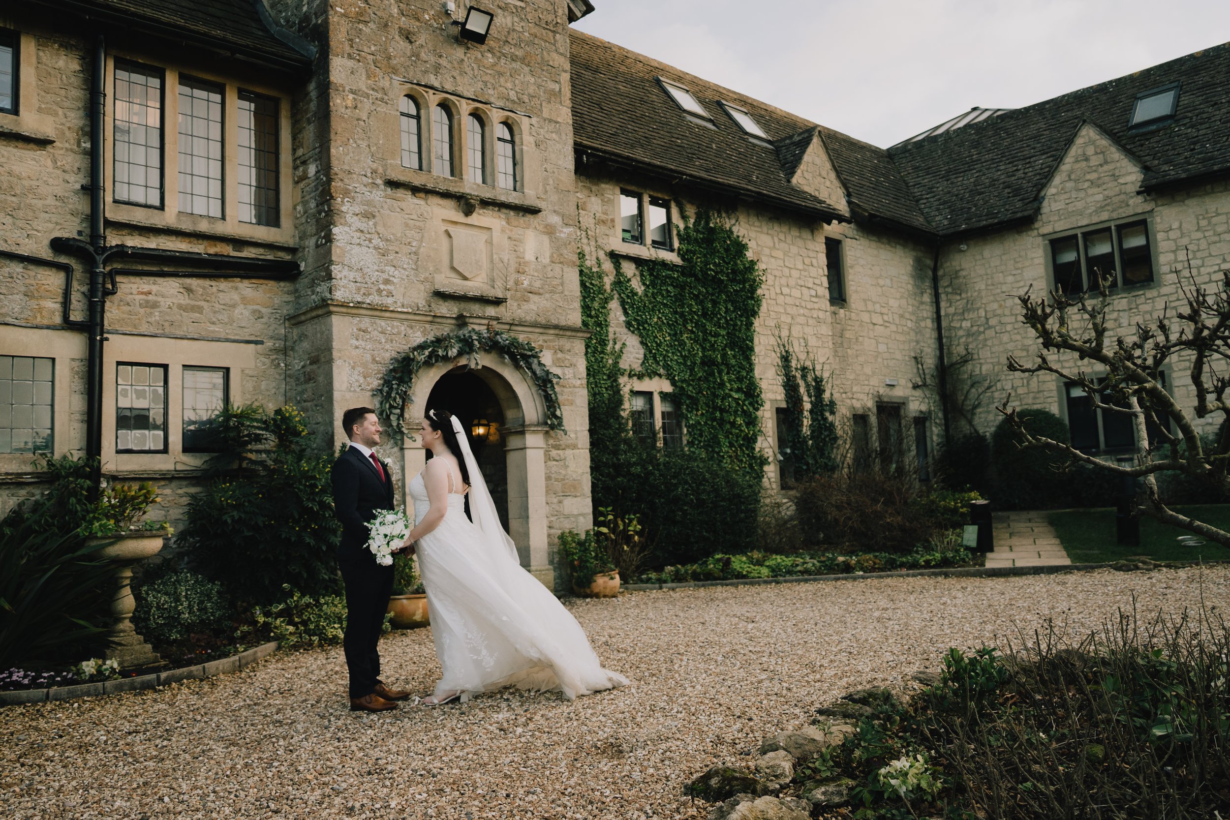 A bride and groom holding hands and looking at each other in front of Pear Tree taken by Wiltshere Wedding Photographer in winter